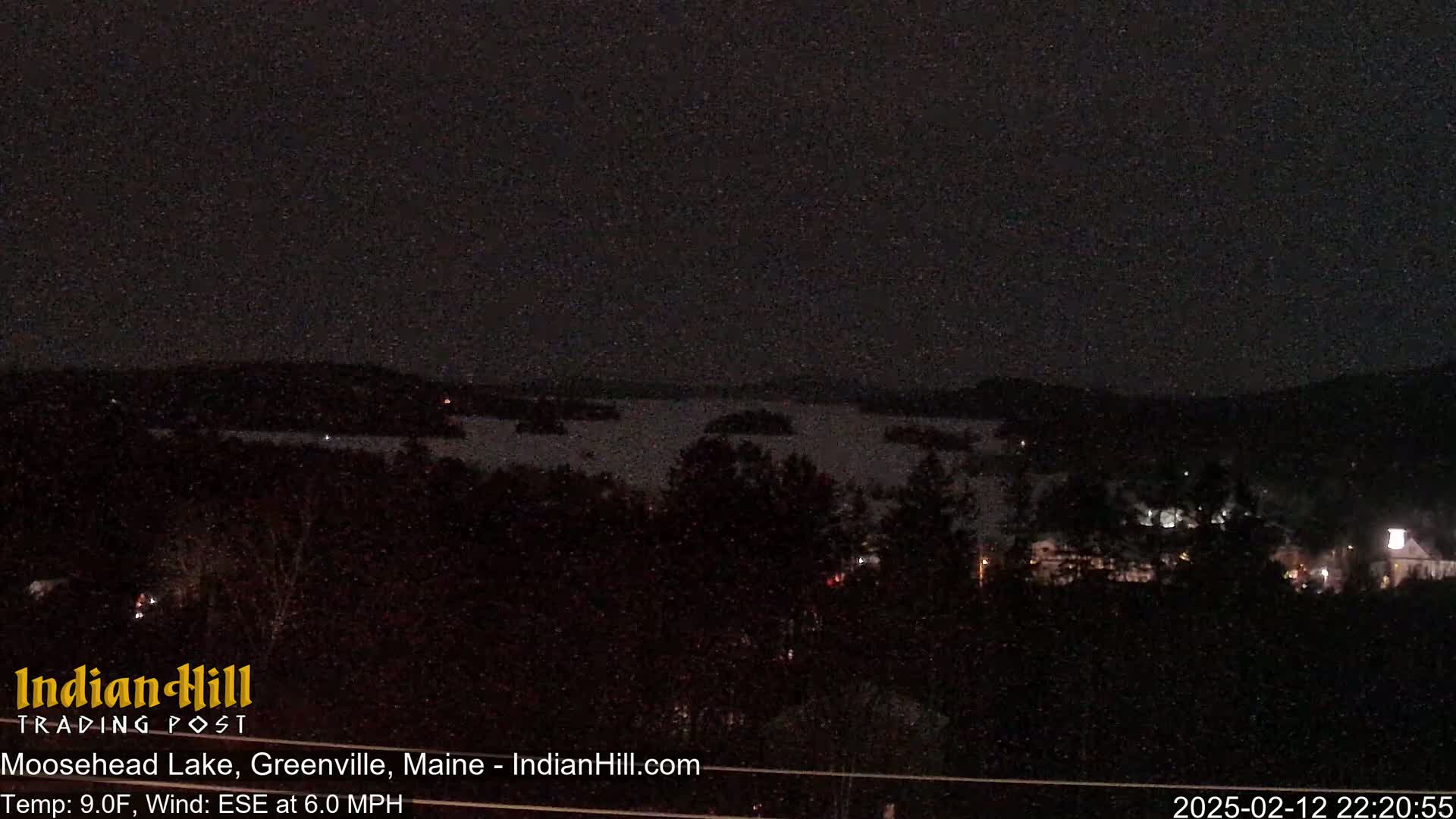 A nighttime view of a lake and surrounding trees, under a dark sky with a temperature of 9 degrees Fahrenheit and a wind blowing from the east-southeast at 6 miles per hour.
