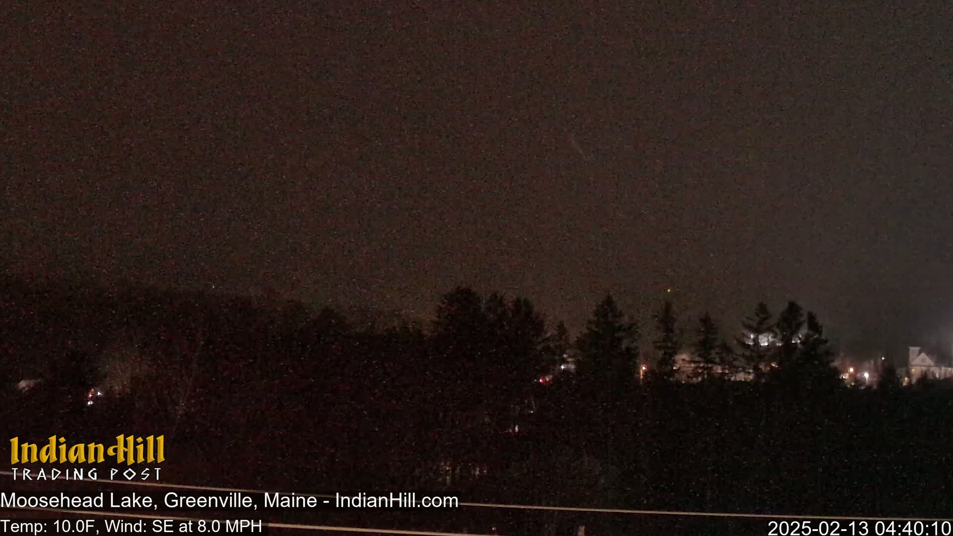 A nighttime view of a dark, tree-lined landscape under a slightly hazy sky, with a southeast wind at 8 miles per hour and a temperature of 10 degrees Fahrenheit.