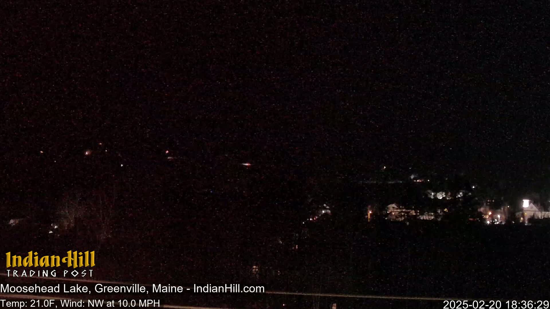 A nighttime long shot of a town with faint lights visible under a dark, clear sky.