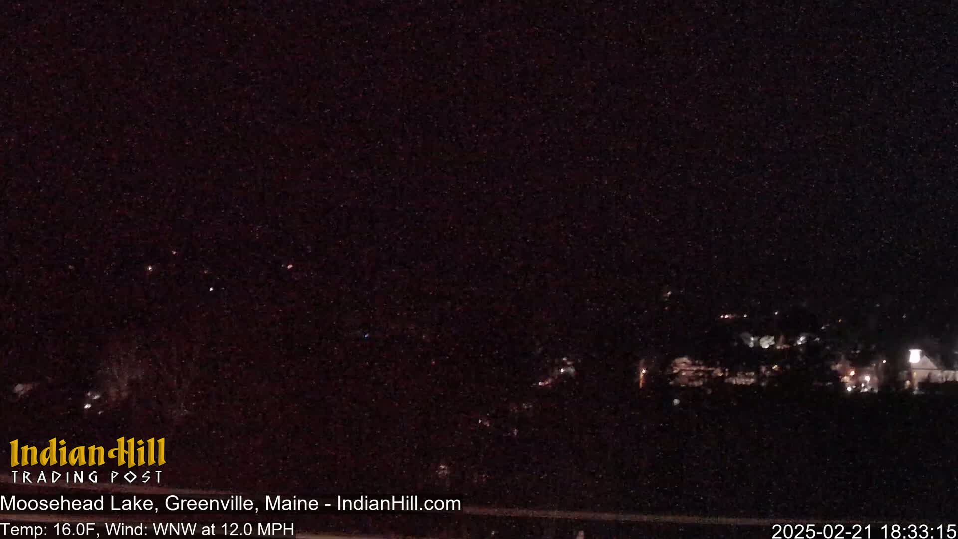 A nighttime view of a dimly lit town under a dark, clear sky with a wind blowing from the west-northwest at 12 mph.