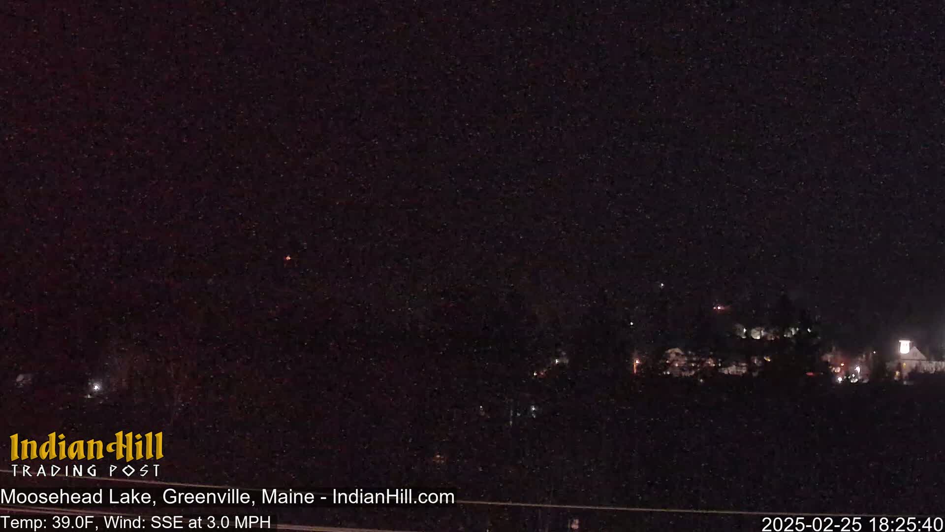 A nighttime view of a dimly lit town under a dark, snowy sky.