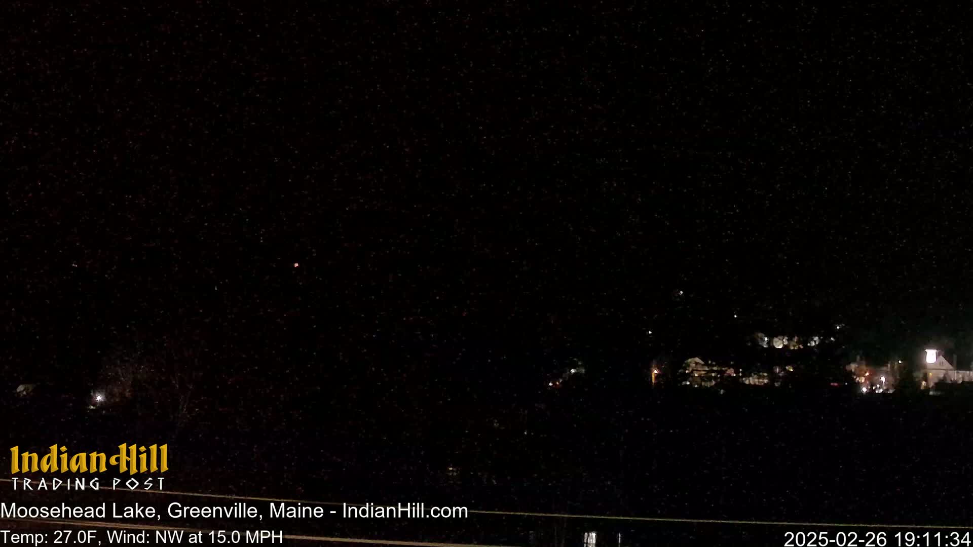A nighttime long shot of a town under a dark, clear sky with a northwest wind at 15 mph and a temperature of 27°F.