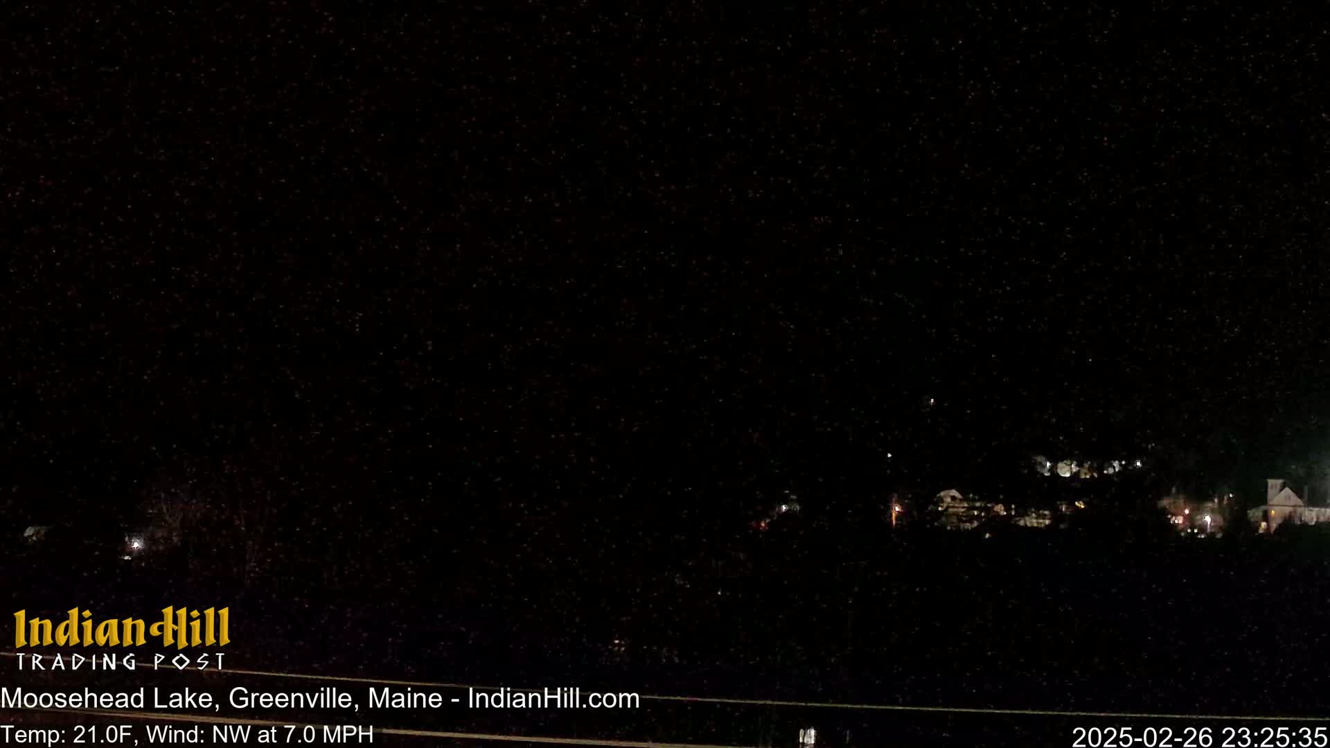 A nighttime view of a dimly lit town under a dark, clear sky with a northwest wind at 7.0 mph and a temperature of 21 degrees Fahrenheit.