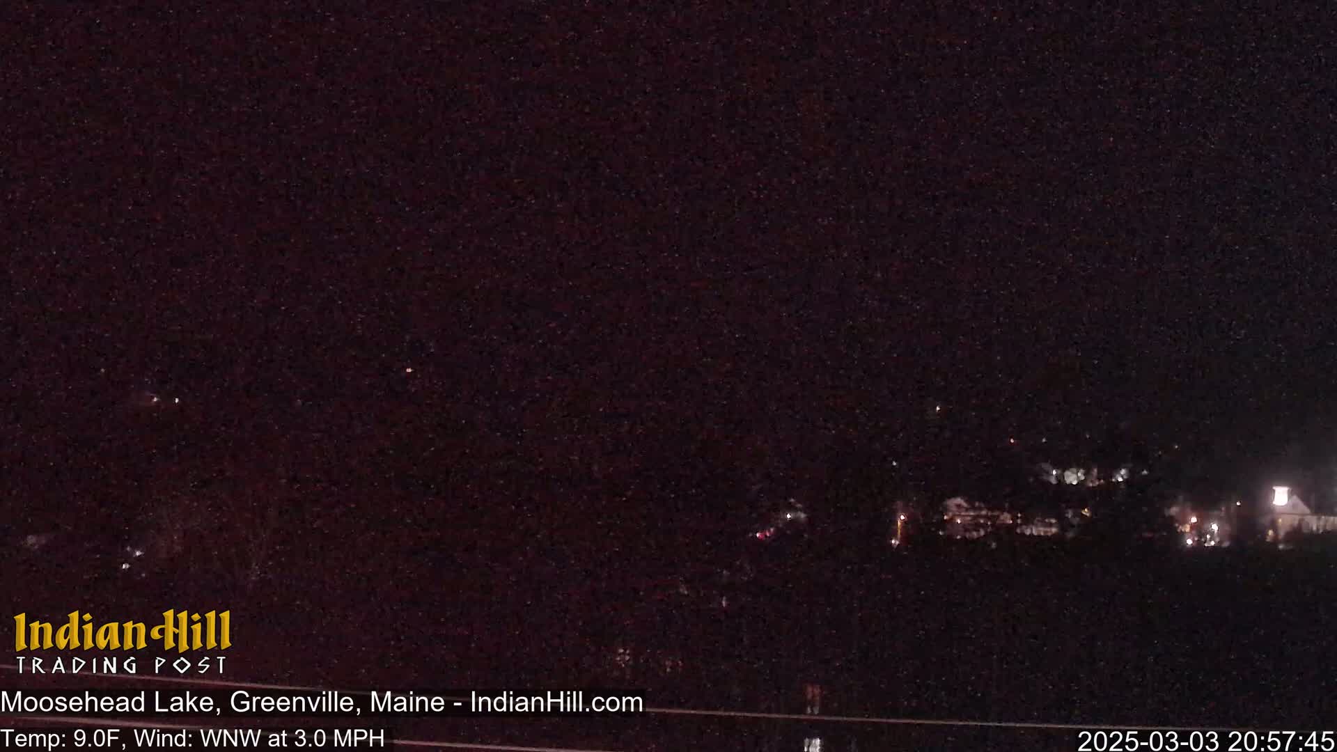 A nighttime long shot of a dimly lit town under a dark, starry sky with a temperature of 9 degrees Fahrenheit and a wind blowing from the west-northwest at 3 miles per hour.
