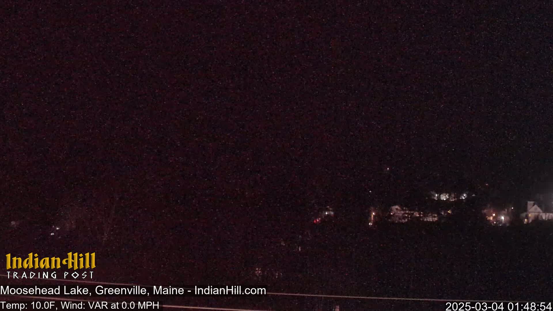 A nighttime view of a dark, sparsely lit landscape under a clear, starlit sky.