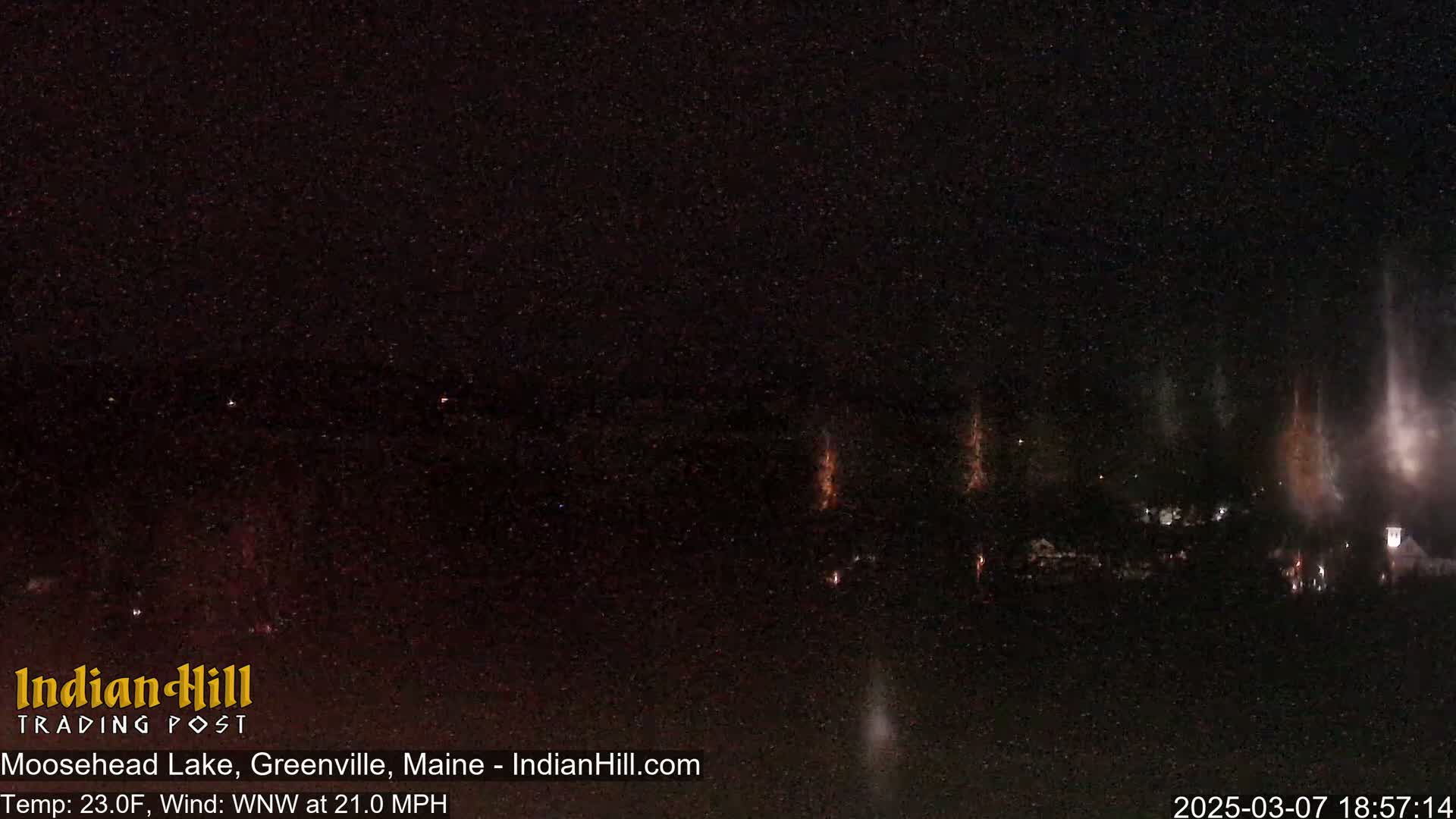 A nighttime view of fireworks over a dark body of water under a starry sky with a wind blowing from the west-northwest at 21 mph.