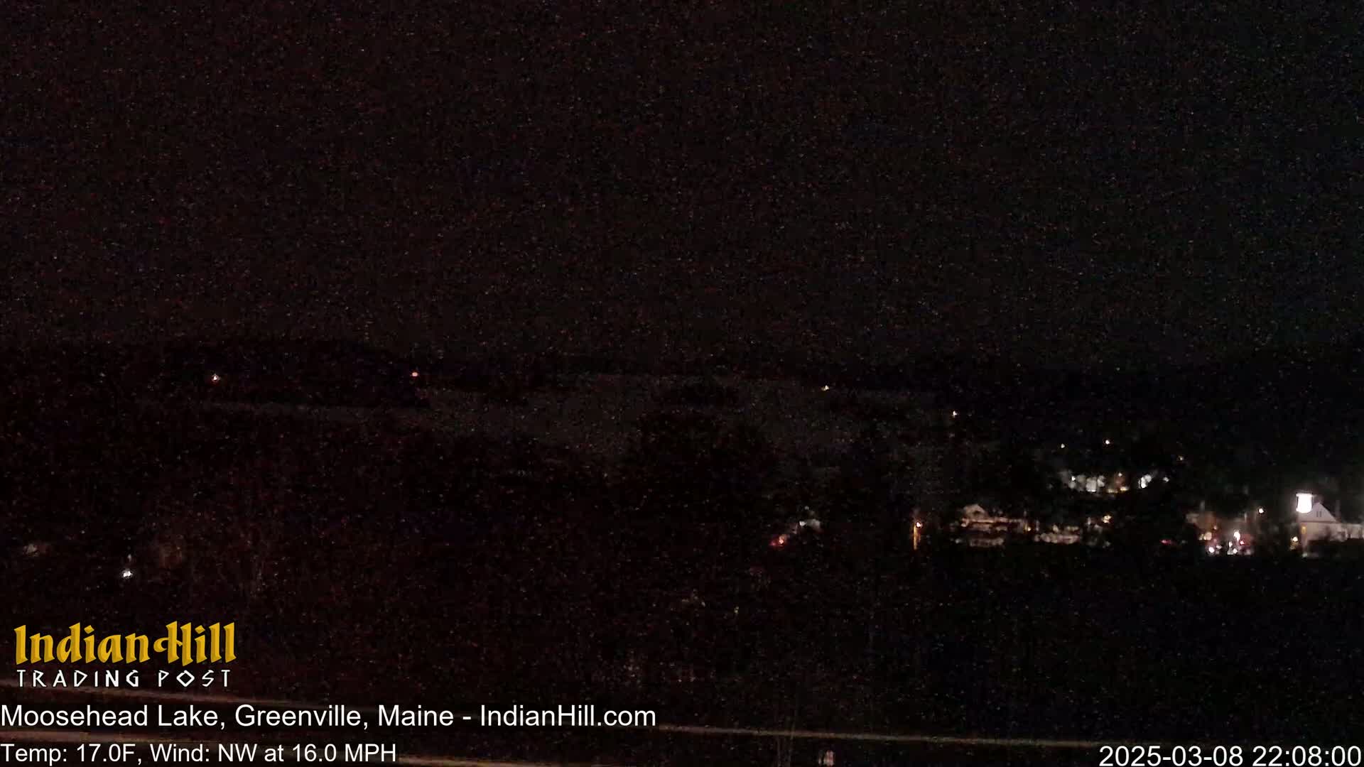 A nighttime view of a lake and distant lights under a dark, clear sky with a northwest wind at 16.0 mph and a temperature of 17 degrees Fahrenheit.
