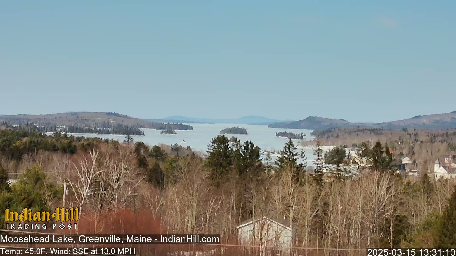 A partly frozen lake with numerous islands is seen from an elevated vantage point on a clear, sunny day with a 13 mph wind.