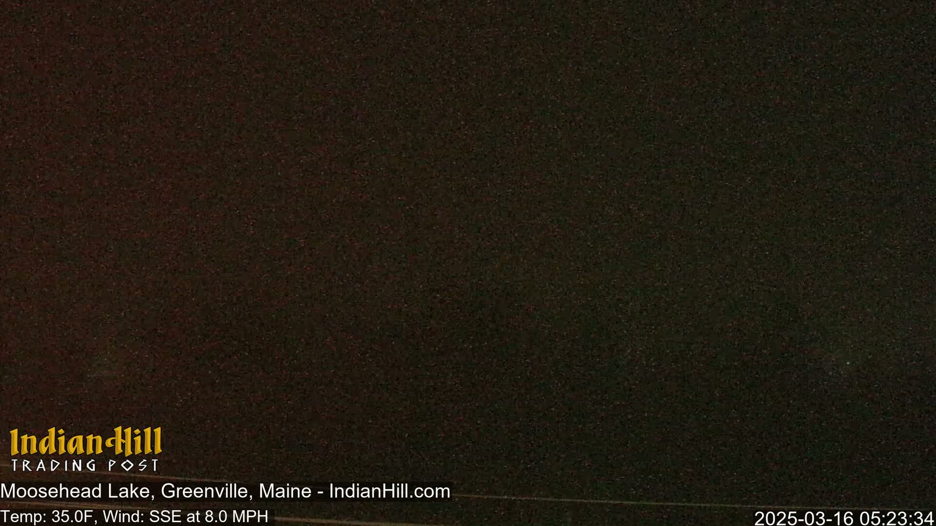 A dark, nighttime image of a mostly featureless scene shows a dark sky with a few indistinct specks.