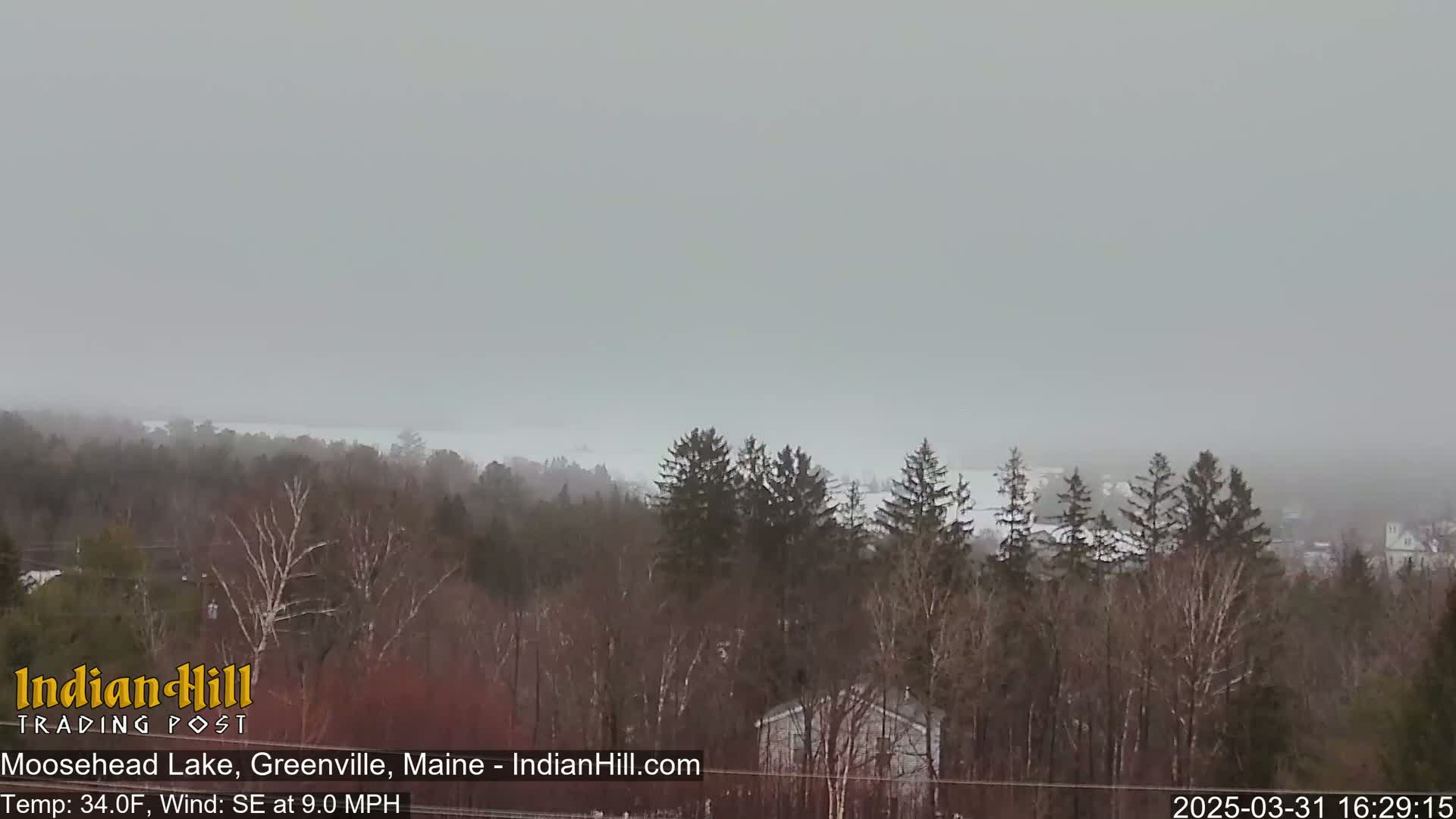 A hazy, snowy view of Moosehead Lake and a wooded landscape is visible from a distance.