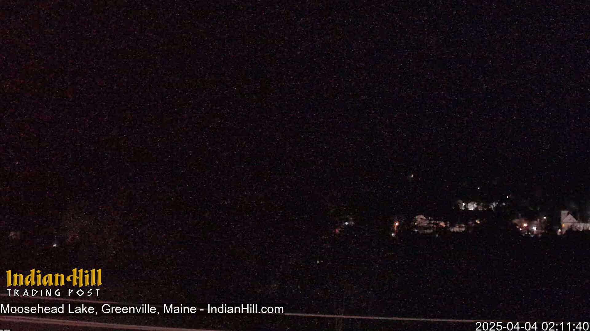 A nighttime, long-range view of a dark landscape with a few distant lights visible.