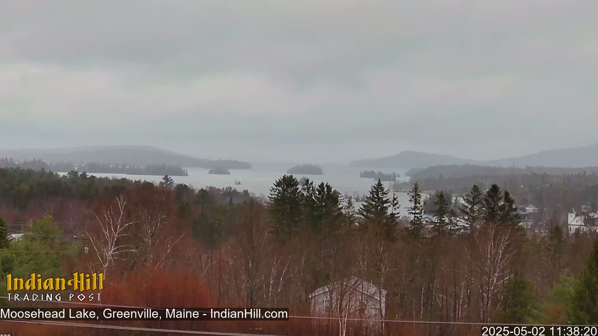 A hazy, overcast view of a lake dotted with islands and surrounded by a forest of mostly bare trees.