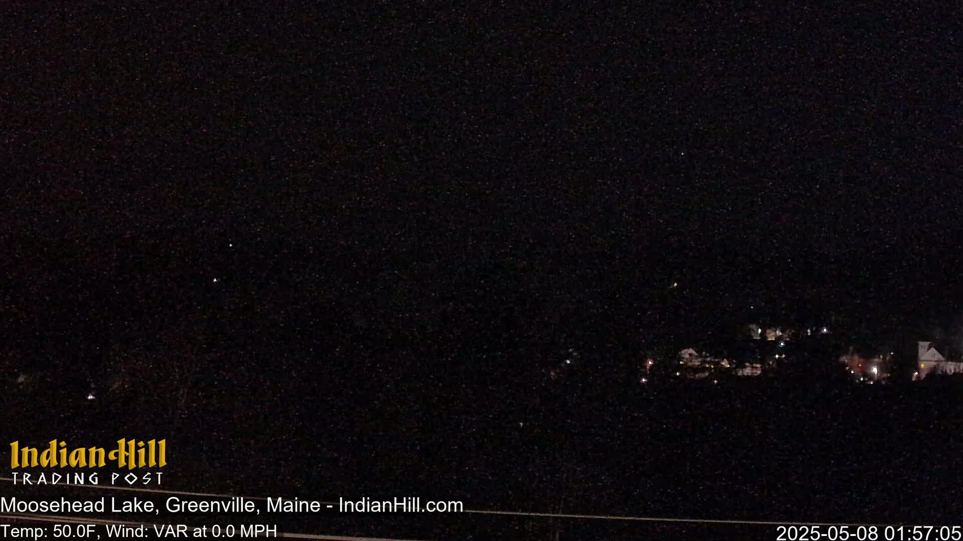A nighttime long shot of a small town illuminated by scattered lights under a clear, starry sky.