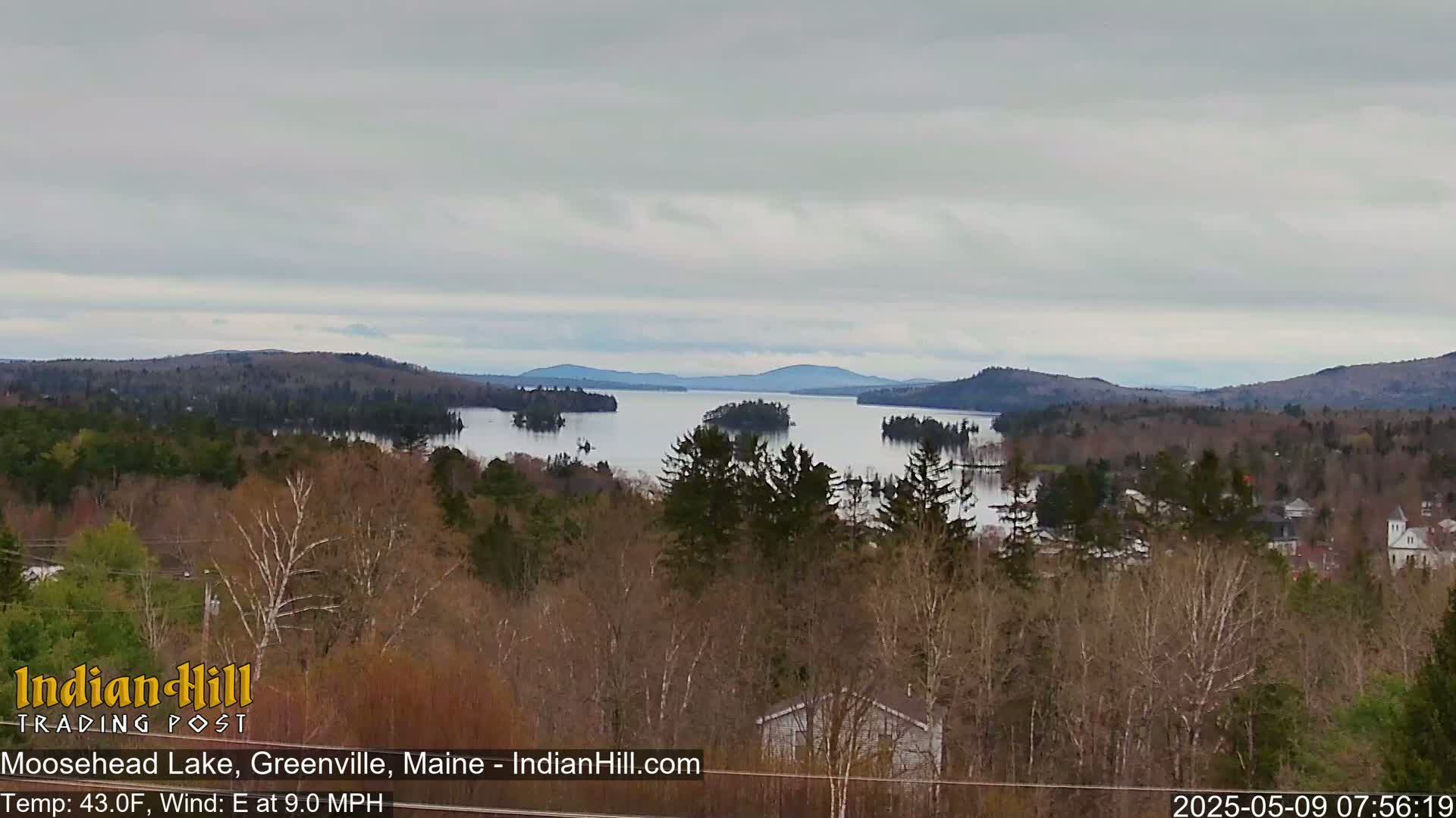 A long lake stretches between forested hills under an overcast sky.