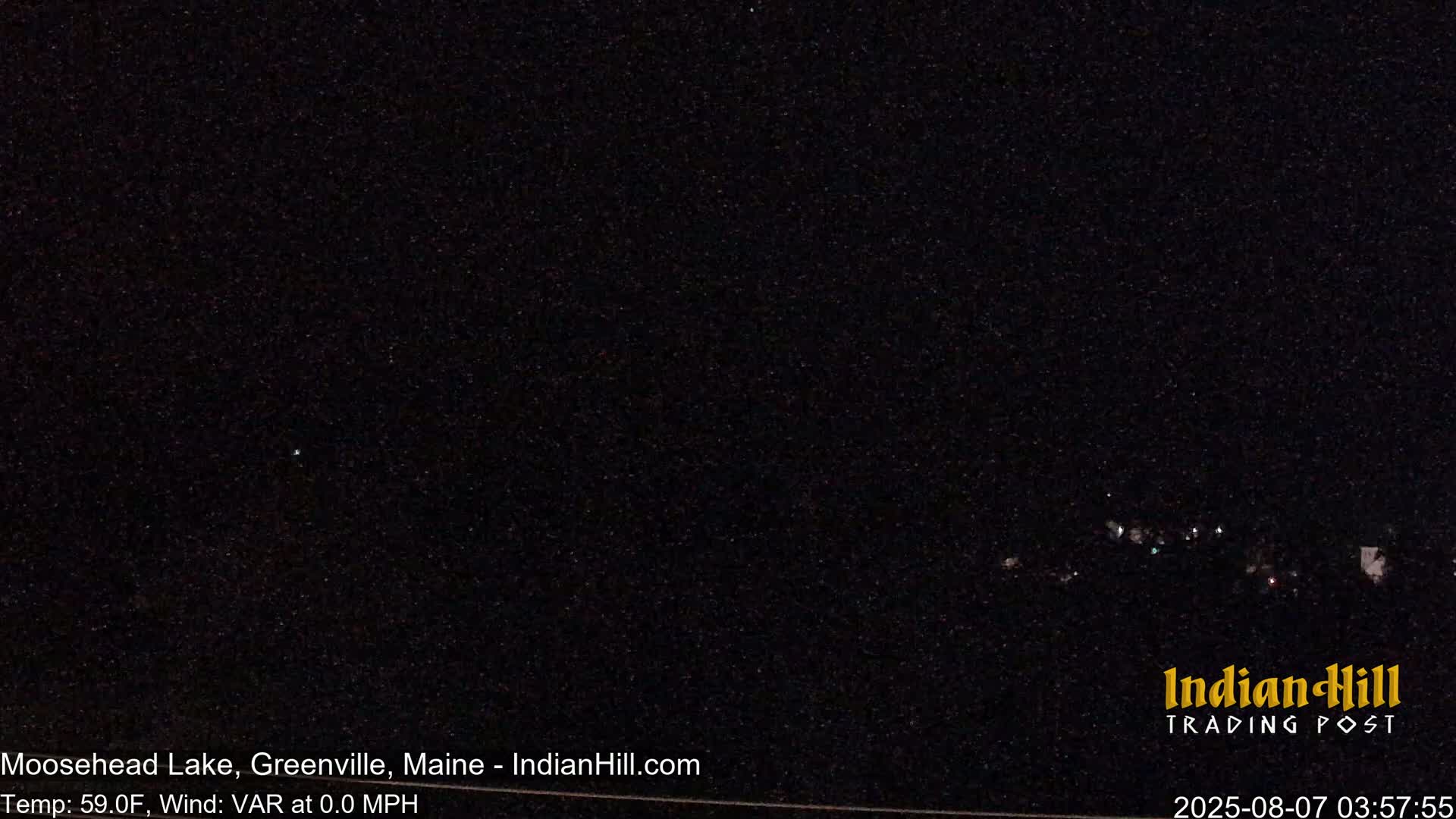A nighttime long shot shows a dark sky with a few faint lights in the distance under calm, clear conditions.