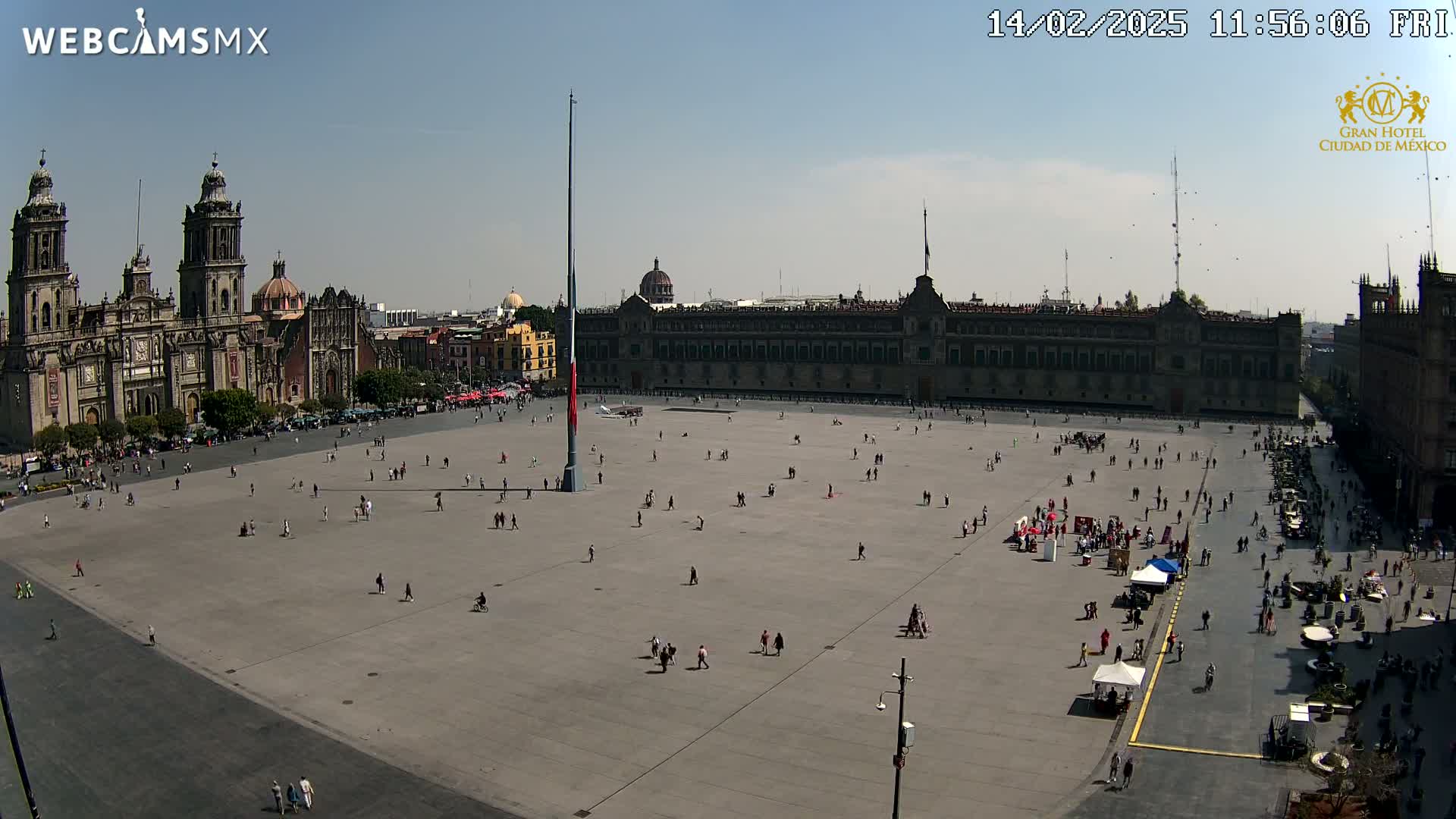 A large plaza with a few people scattered throughout, overlooked by a cathedral and government buildings under a clear, sunny sky.