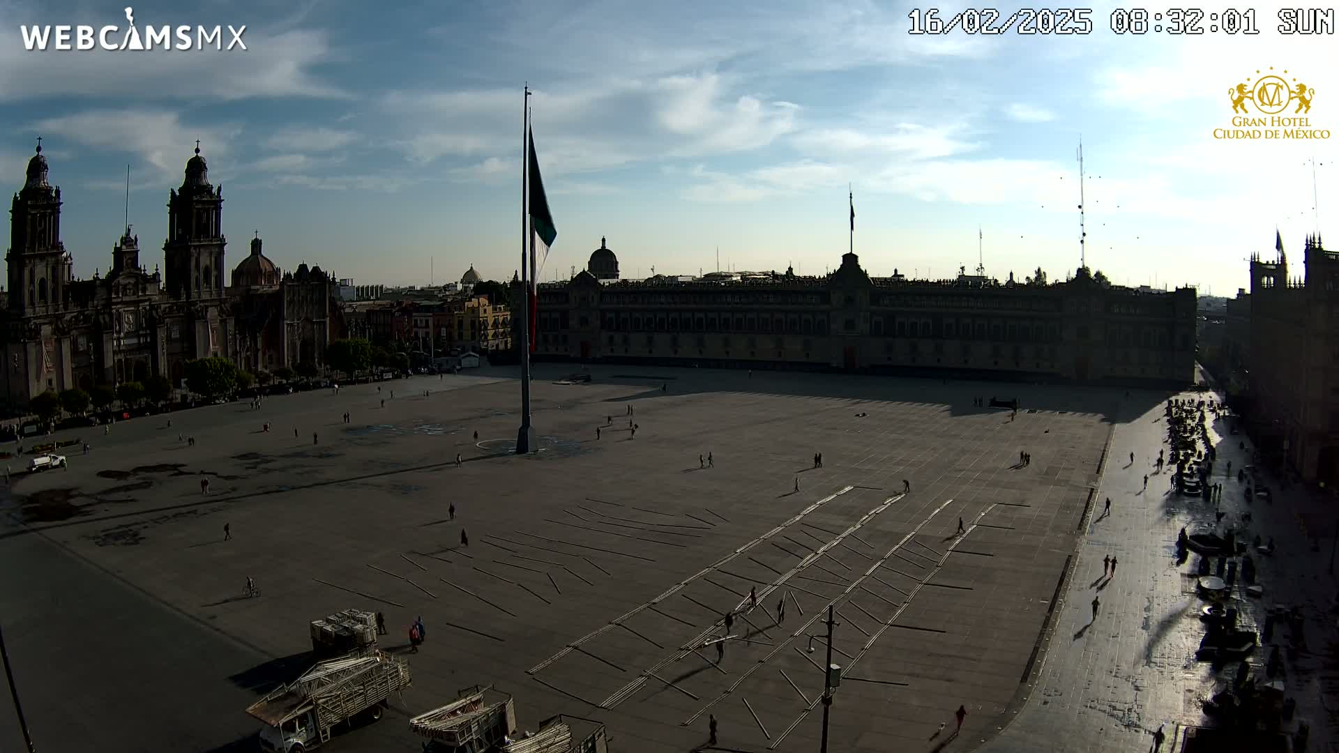 A large plaza with a cathedral and government building is mostly empty under a partly cloudy sky.