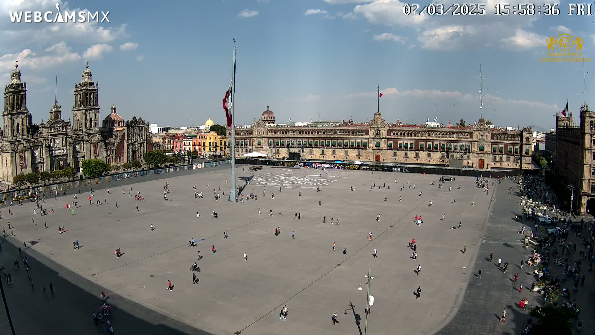 A large plaza with sparsely scattered people, overlooked by a grand cathedral and government building under a mostly sunny sky.