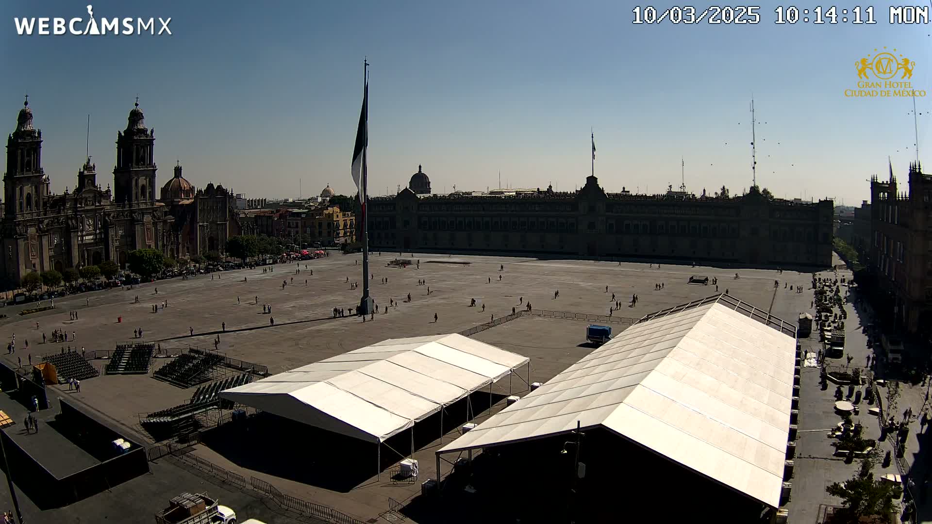 A large plaza with several temporary structures, surrounded by historic buildings under a clear, sunny sky.