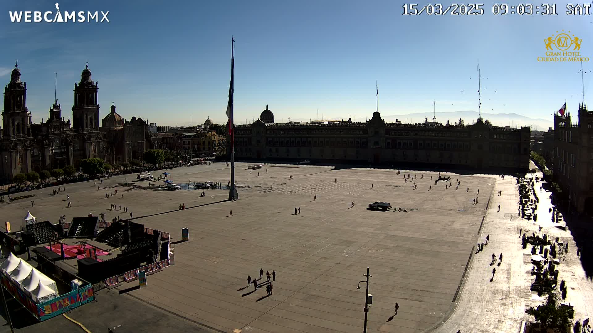 A large plaza with a cathedral and government building is mostly empty under a clear, sunny sky.