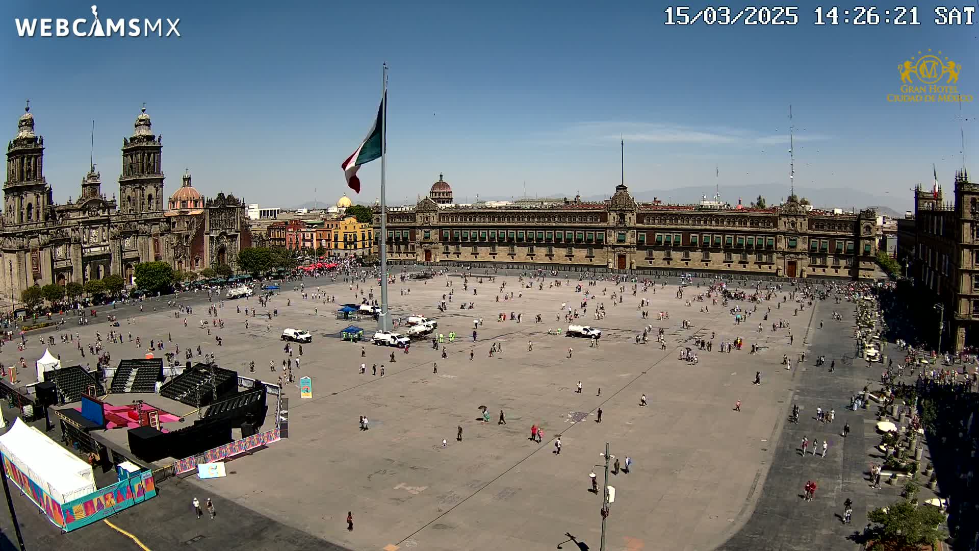 A large plaza with a cathedral and government building is sparsely populated under a clear, sunny sky.
