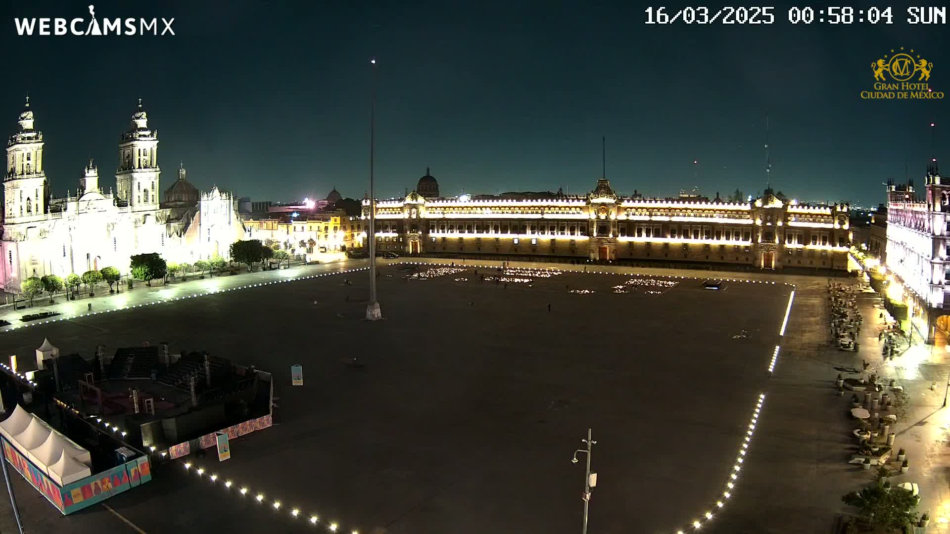 A large, brightly lit plaza at night is surrounded by historical buildings, including a cathedral and palace.
