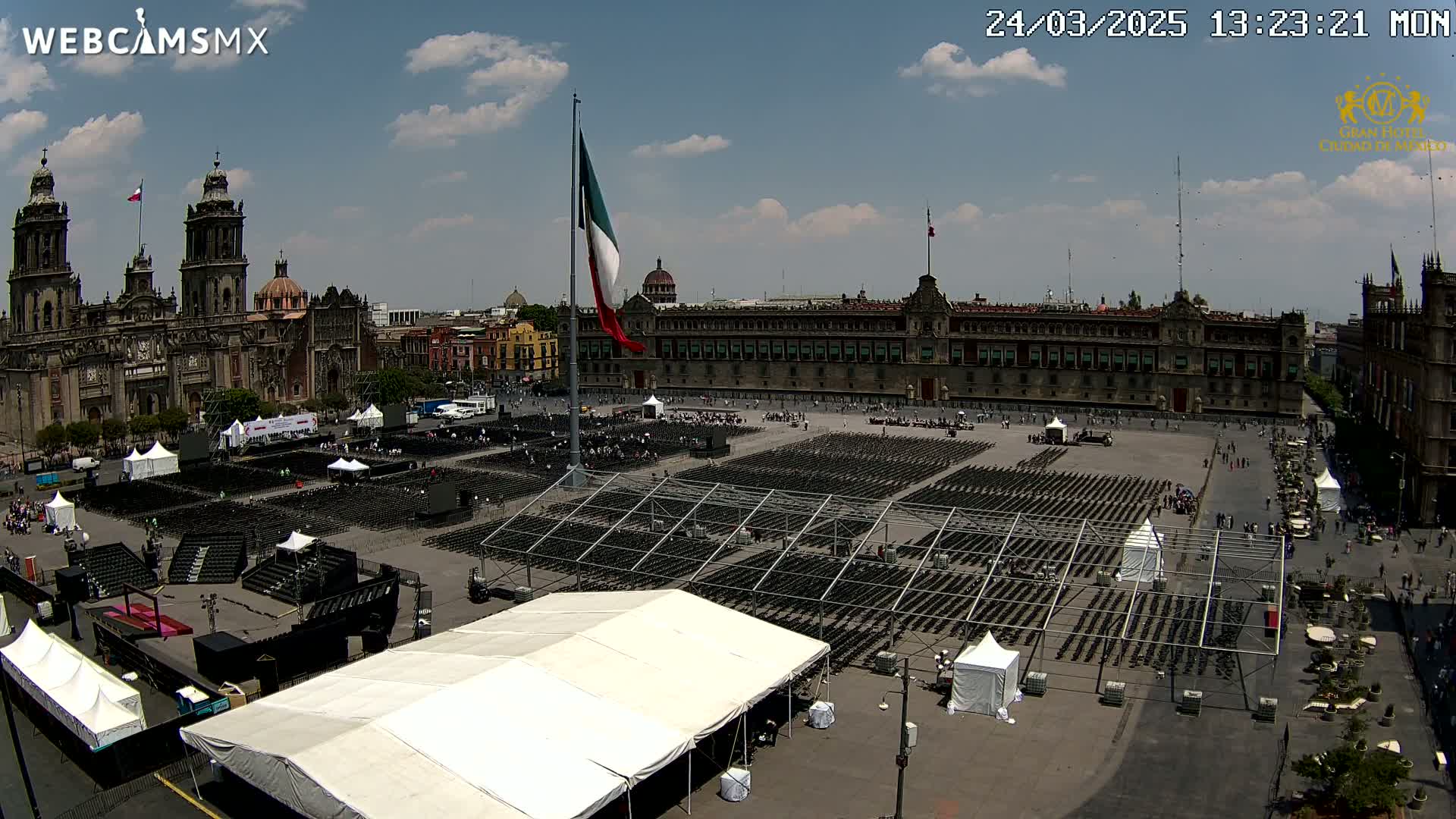 A large plaza with many empty chairs under a mostly sunny sky, overlooked by a large cathedral and government building.