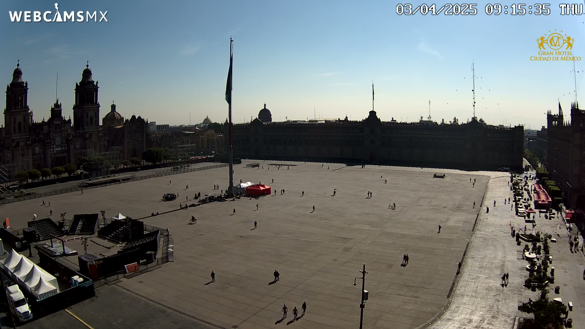 A large plaza with a few people sparsely scattered across it, surrounded by historic buildings under a clear sunny sky.