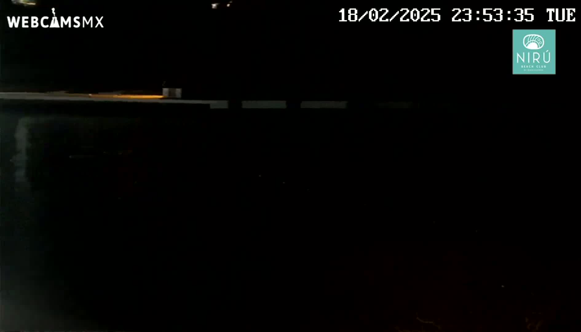 A nighttime image shows a dark, possibly empty, area with a faint light source in the distance.