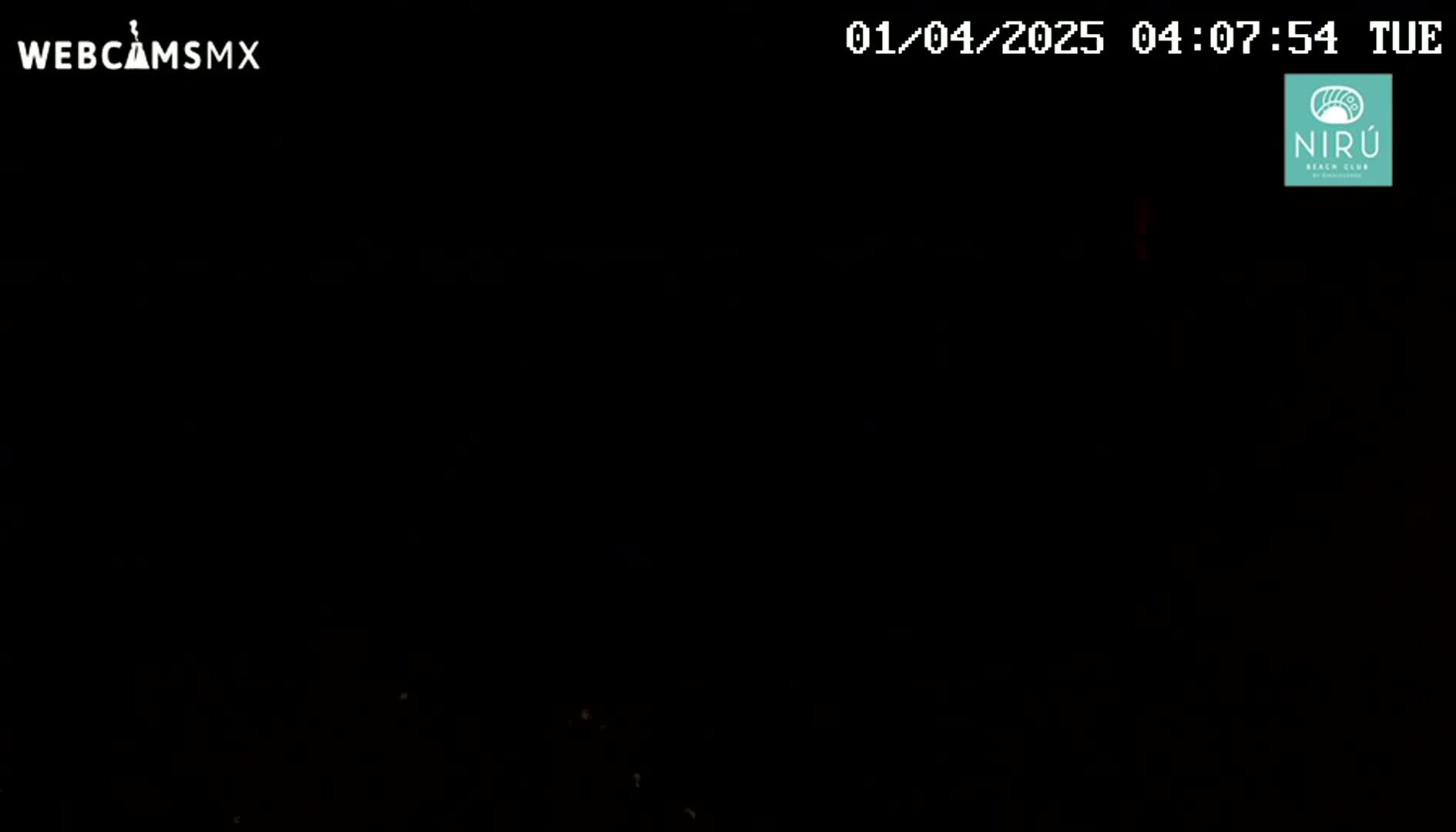 The image shows a completely dark scene at night with a few faint, distant lights visible.