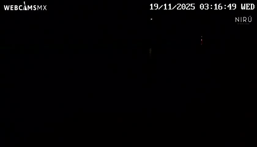 An extremely dark night scene shows only a few faint, pixelated lights barely visible against the black backdrop.