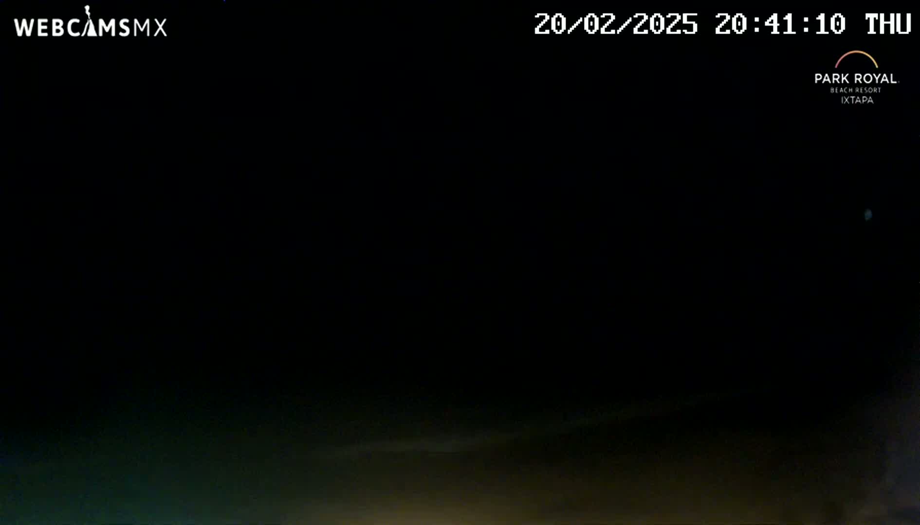 A dark nighttime scene shows a mostly clear sky with faint clouds near the horizon.