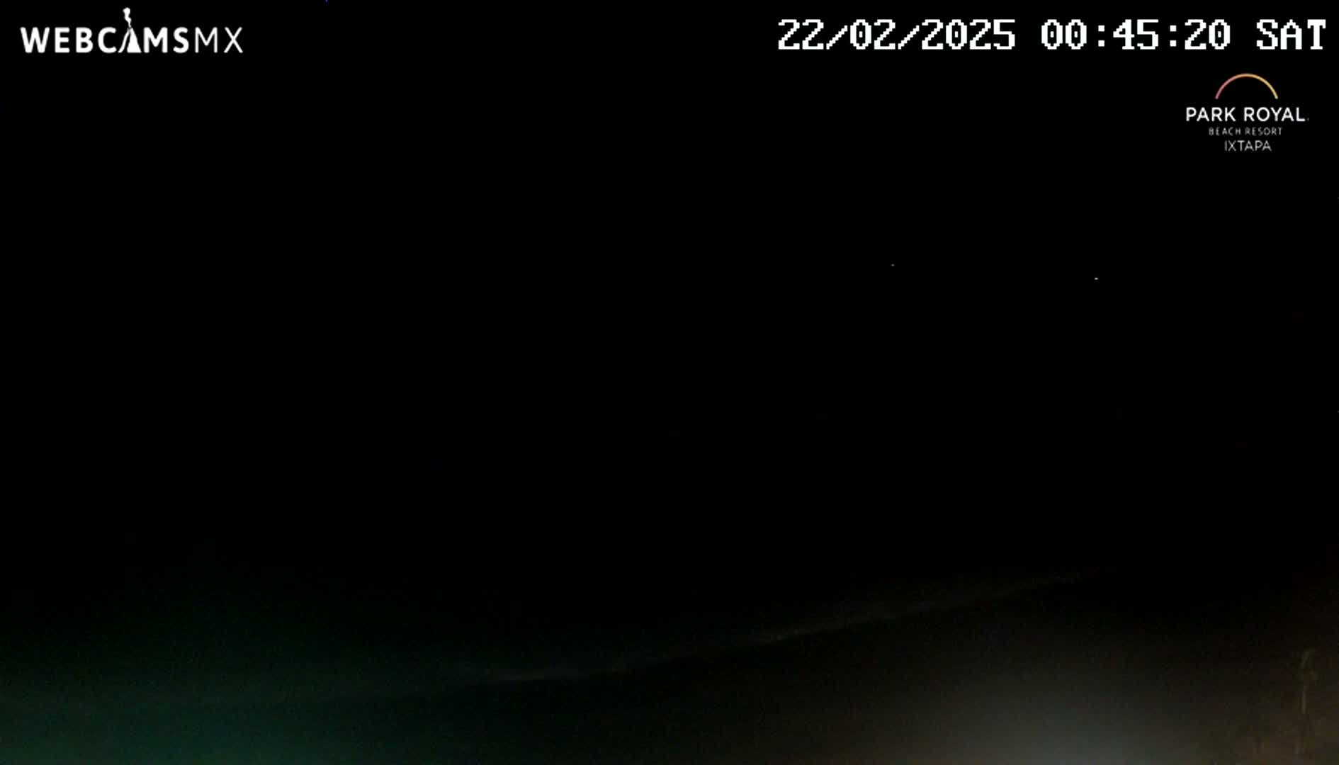 A dark, nighttime scene shows a mostly black horizon with a hint of a dark body of water at the bottom.