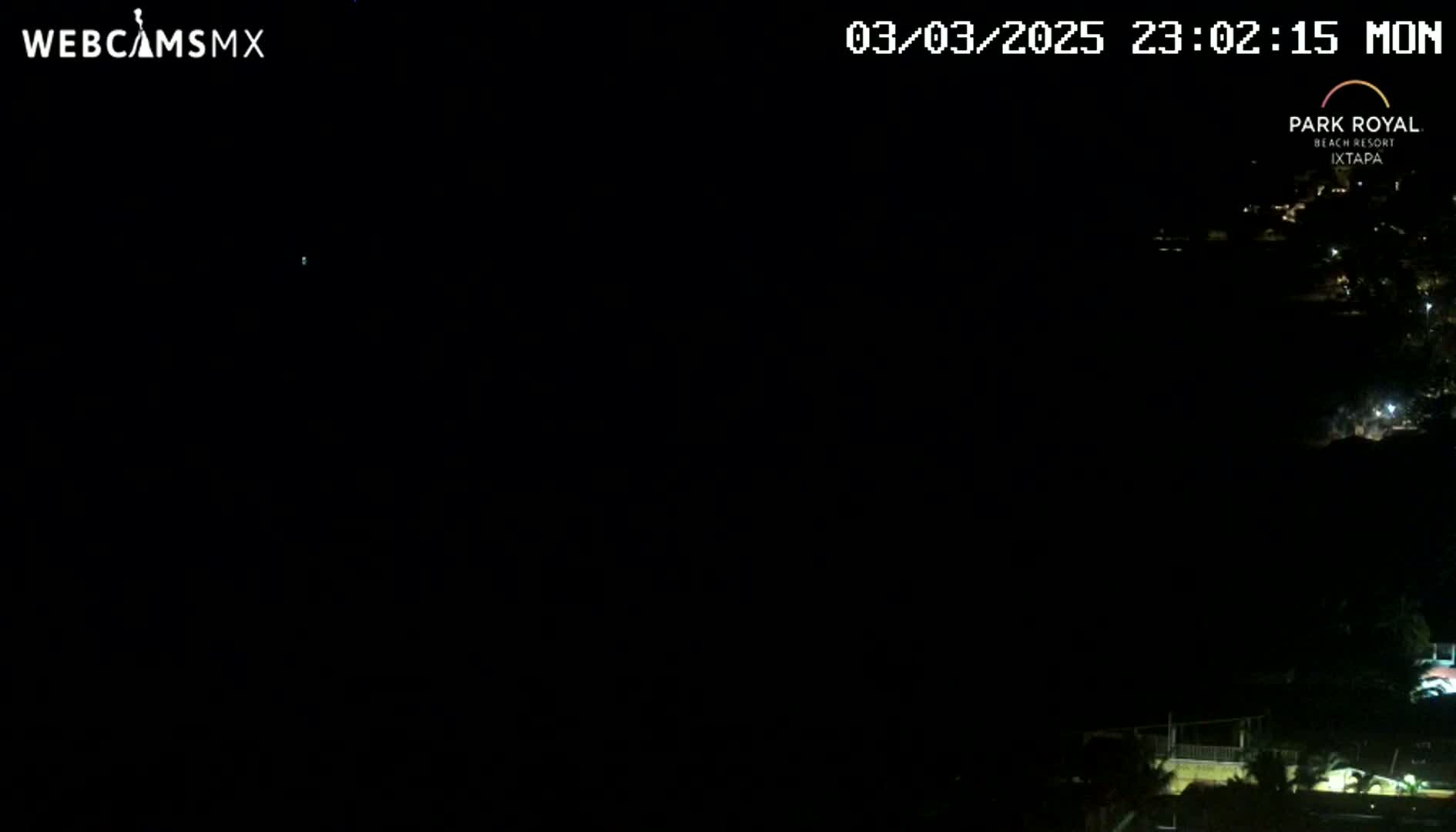 A nighttime, dark view overlooking a dimly lit coastal area.