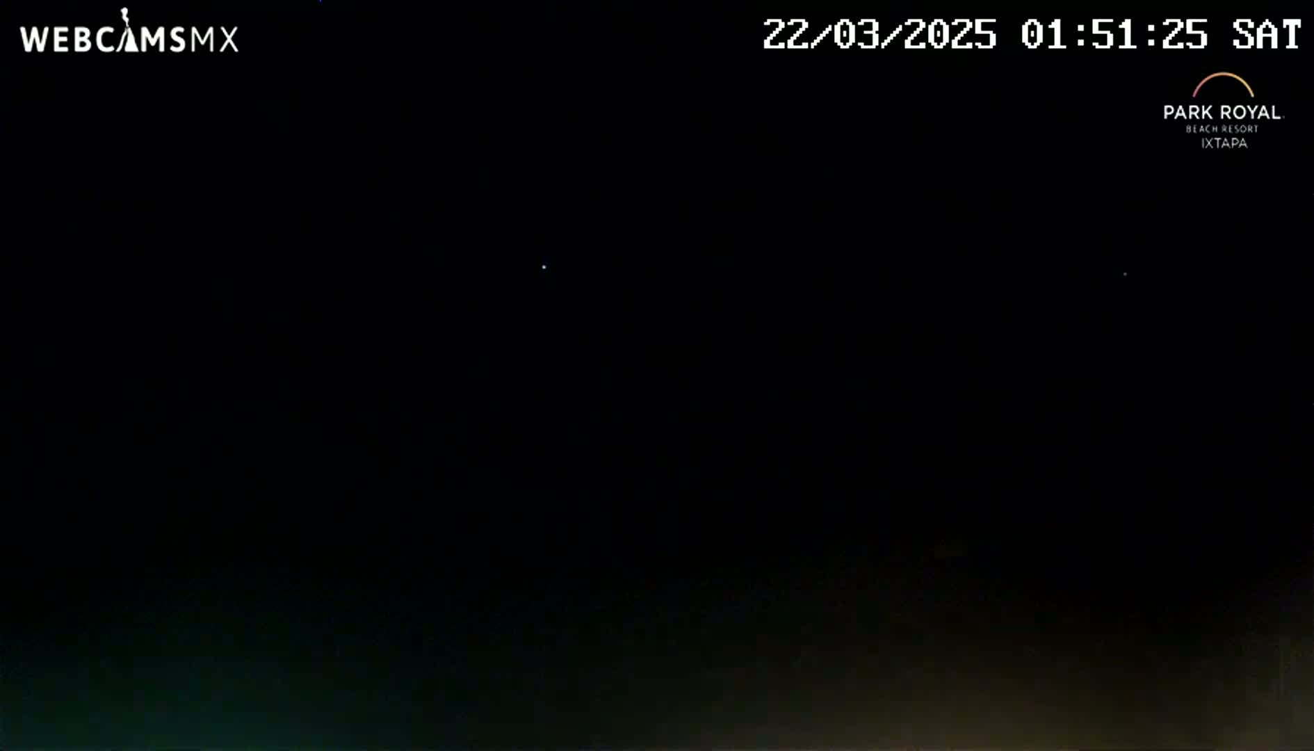 A nighttime, dark scene shows a few faint lights in the sky.
