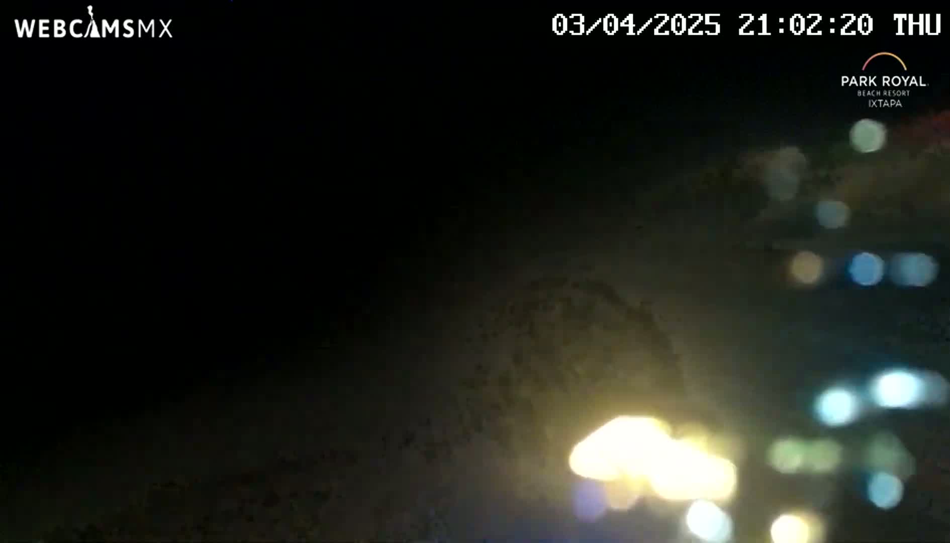 A dark, nighttime scene shows blurry out-of-focus lights in the distance.
