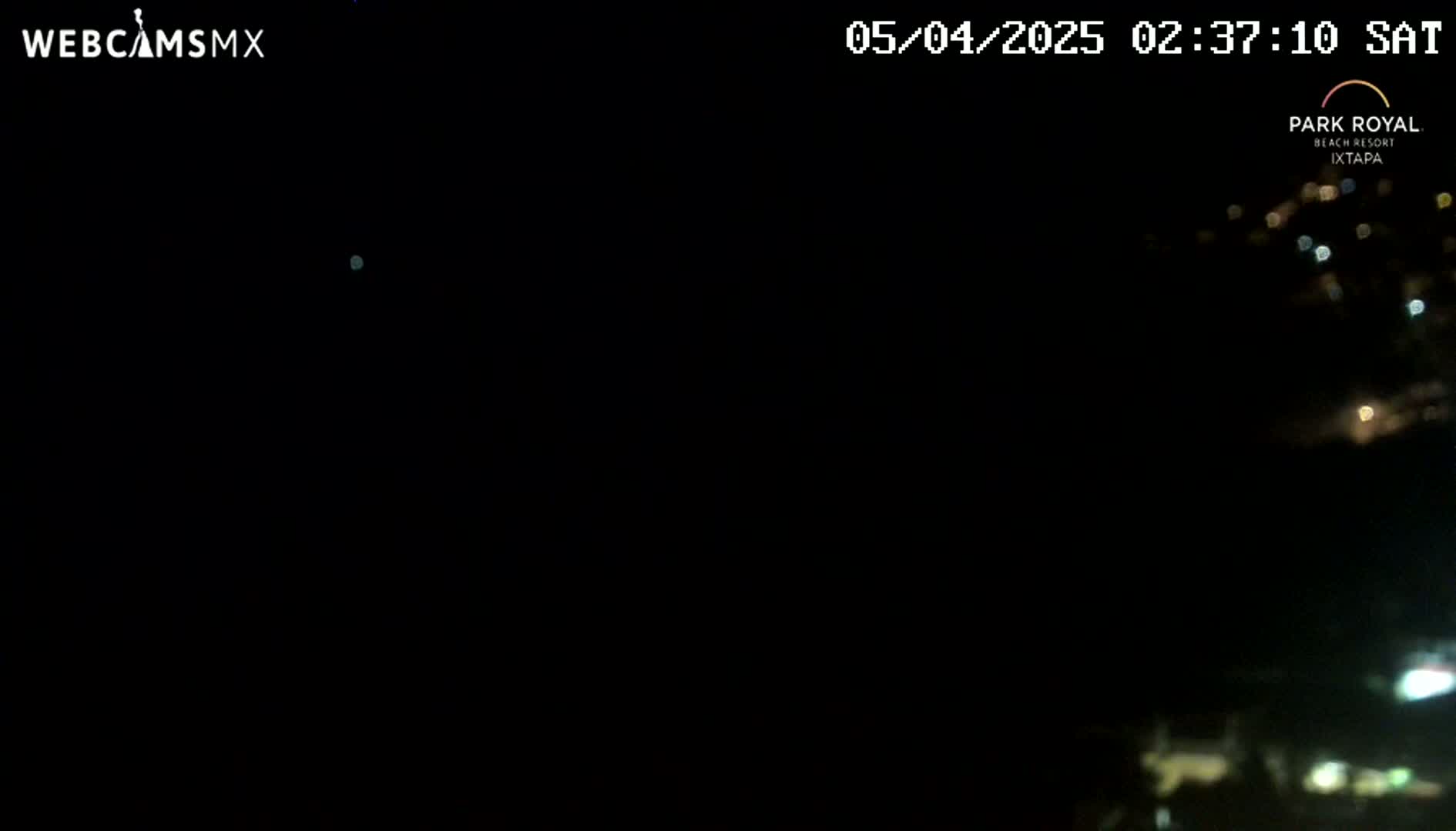 A nighttime long shot shows a dark, clear sky above a distant collection of faint lights.