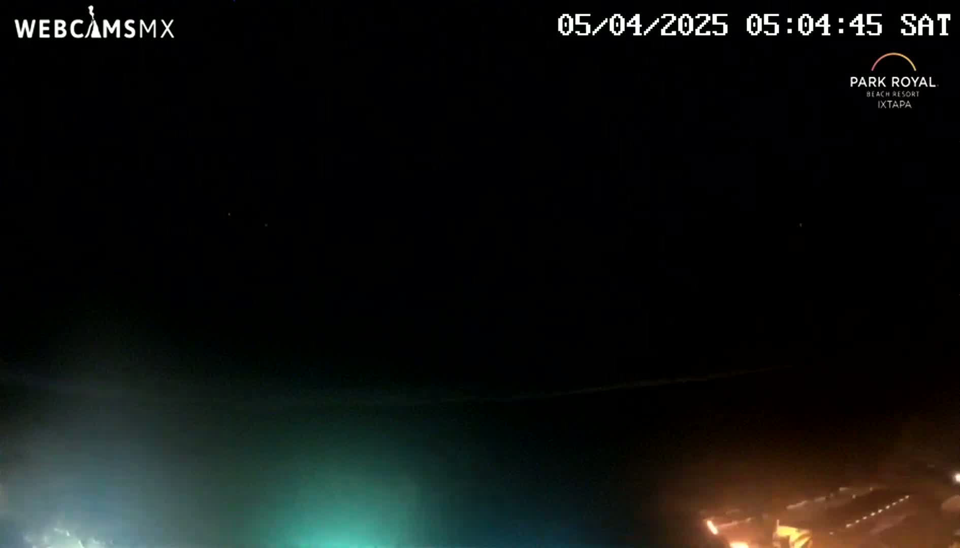 A nighttime, long-distance view shows dimly lit buildings and faint lights on the horizon under a dark, clear sky.