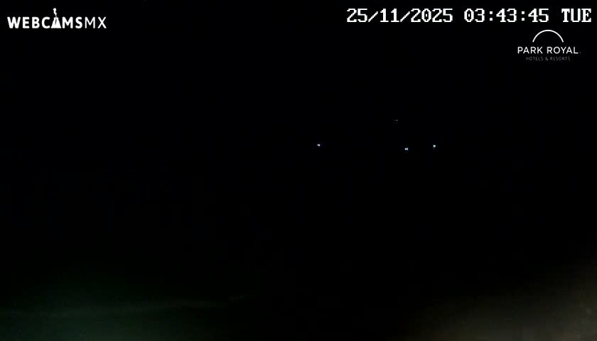 A clear night sky, marked by several faint, distant lights, stretches above a barely visible dark horizon line.