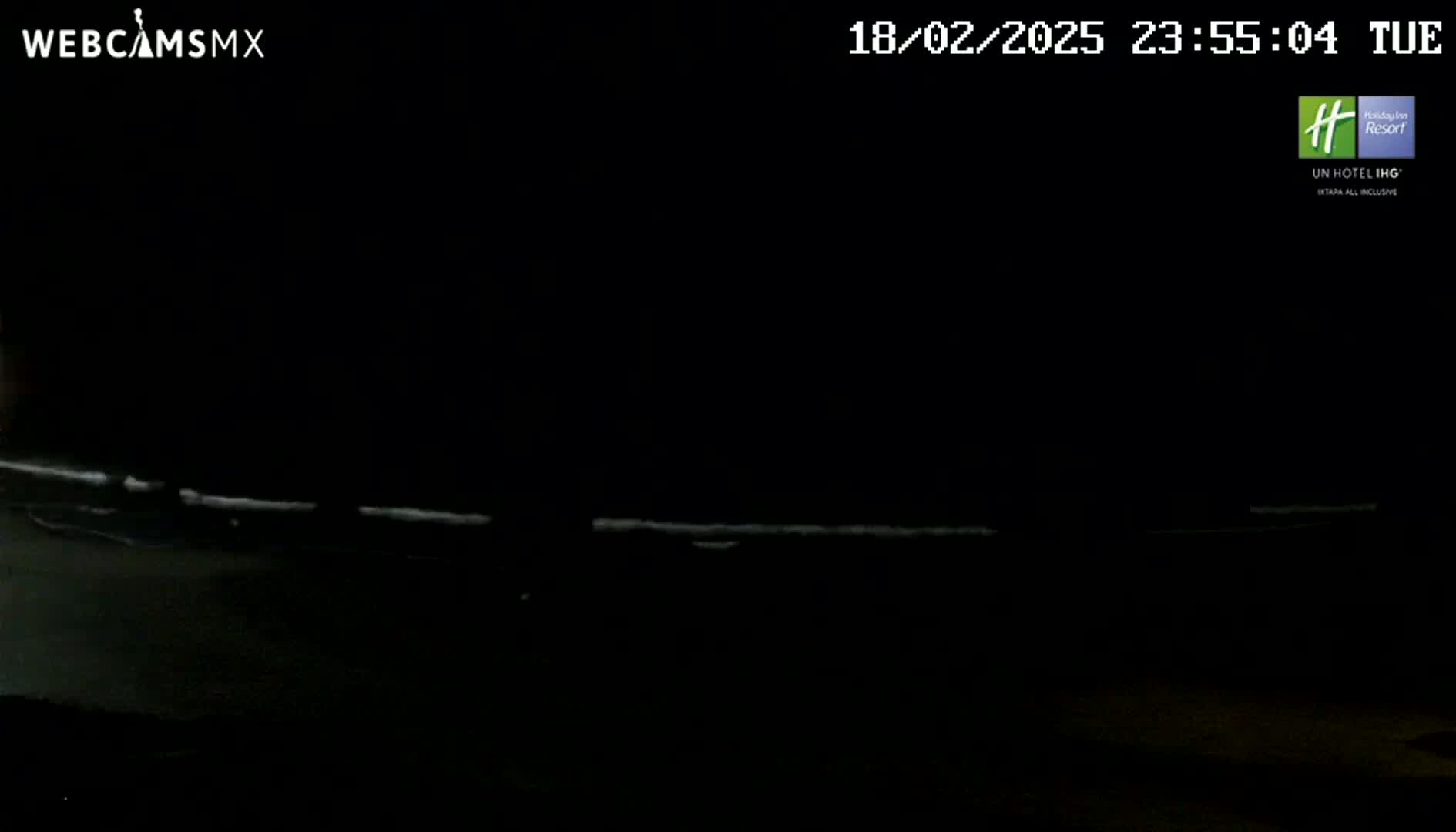 A dark nighttime scene shows a faint, bright line near the bottom of the frame, possibly representing waves or a road.