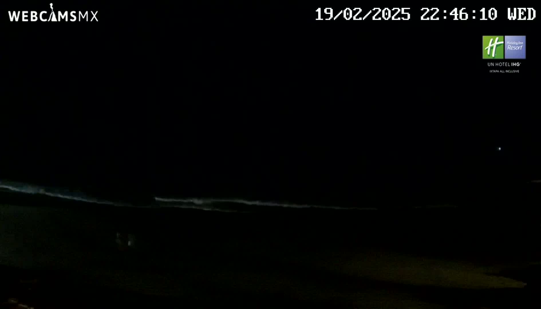 A dark nighttime beach scene shows gently lapping waves under a clear, starlit sky.