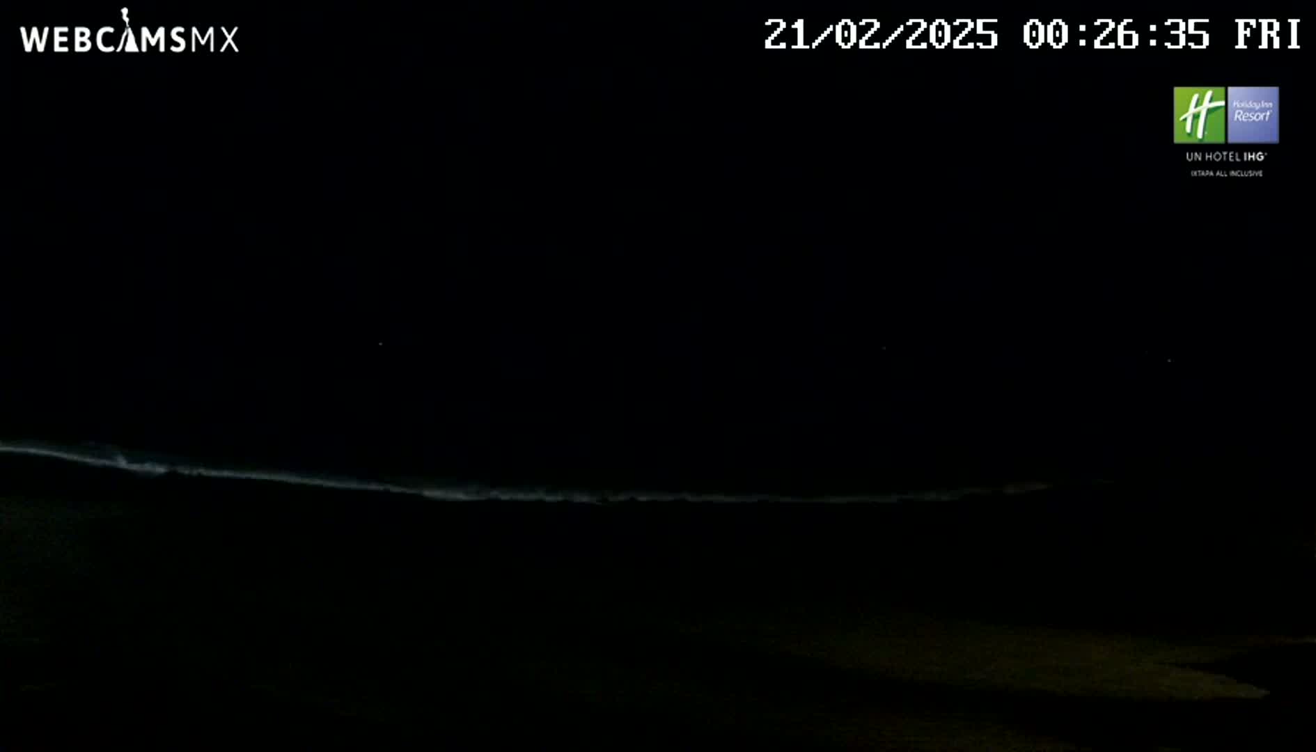 A dark nighttime scene shows a dimly lit ocean with waves at the horizon under a clear sky.