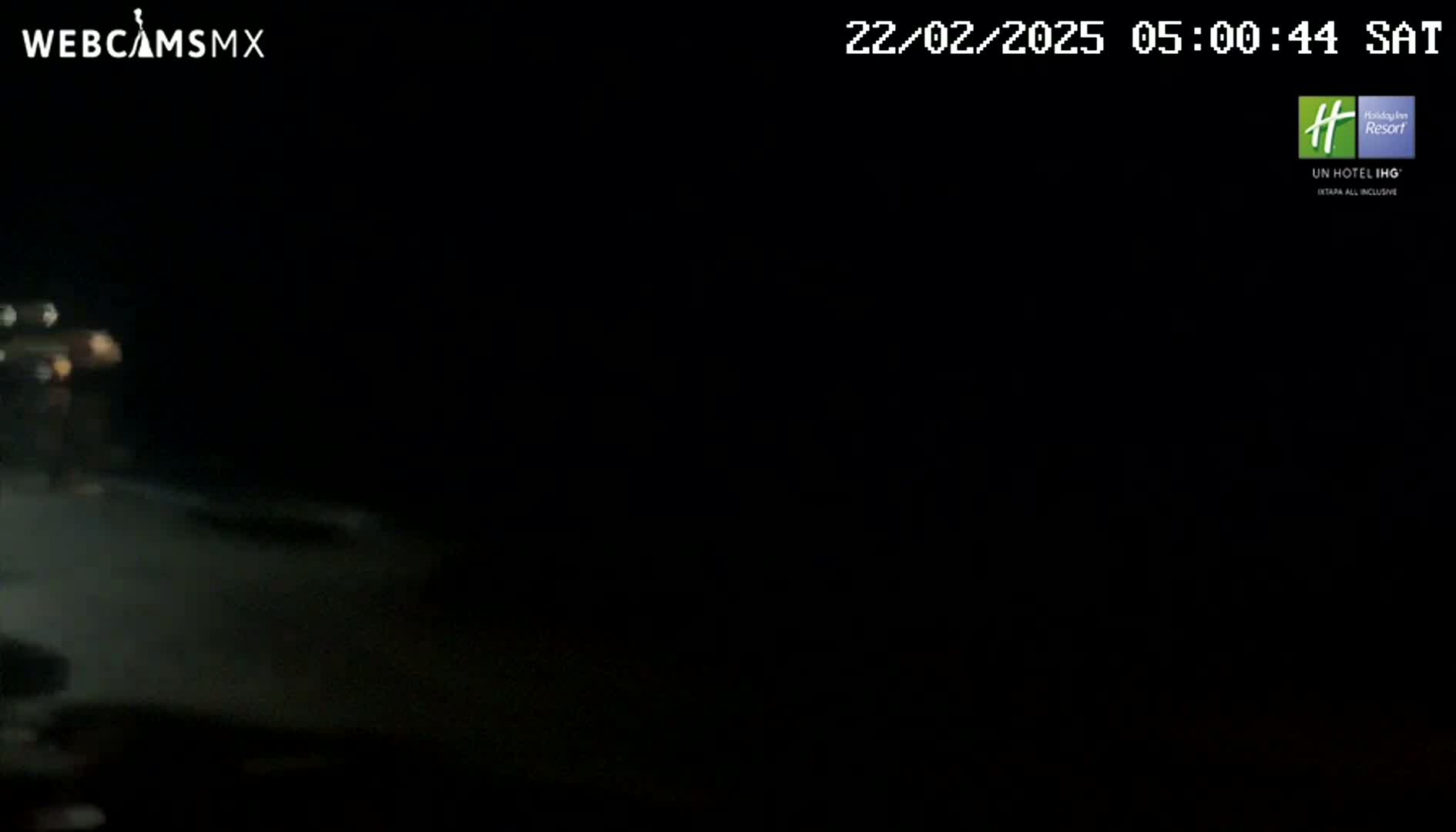 A blurry, dark nighttime image shows a dimly lit road with a vehicle in the distance.