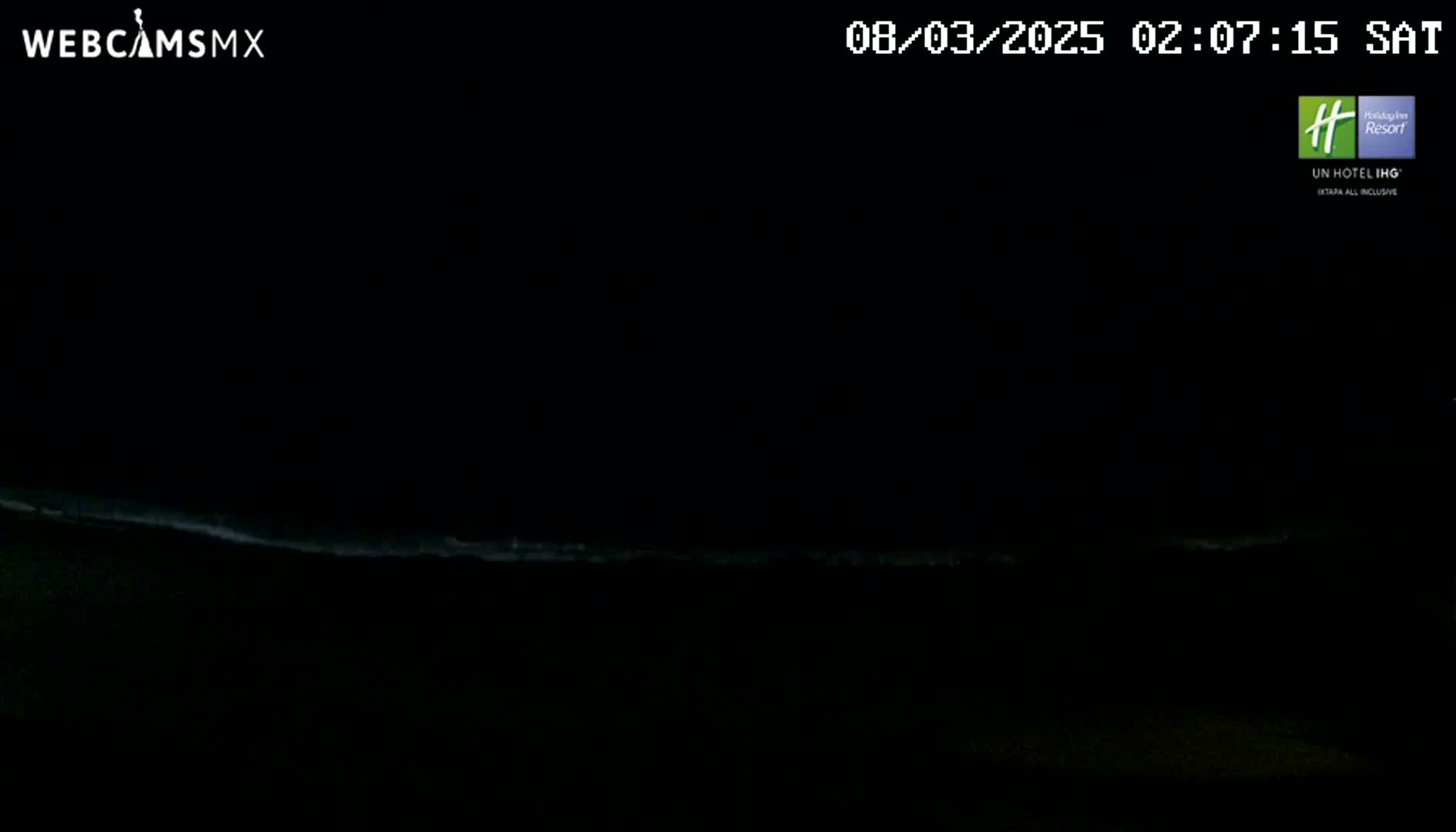 A dark, nighttime scene shows a faint, light-colored line of ocean waves on the horizon.