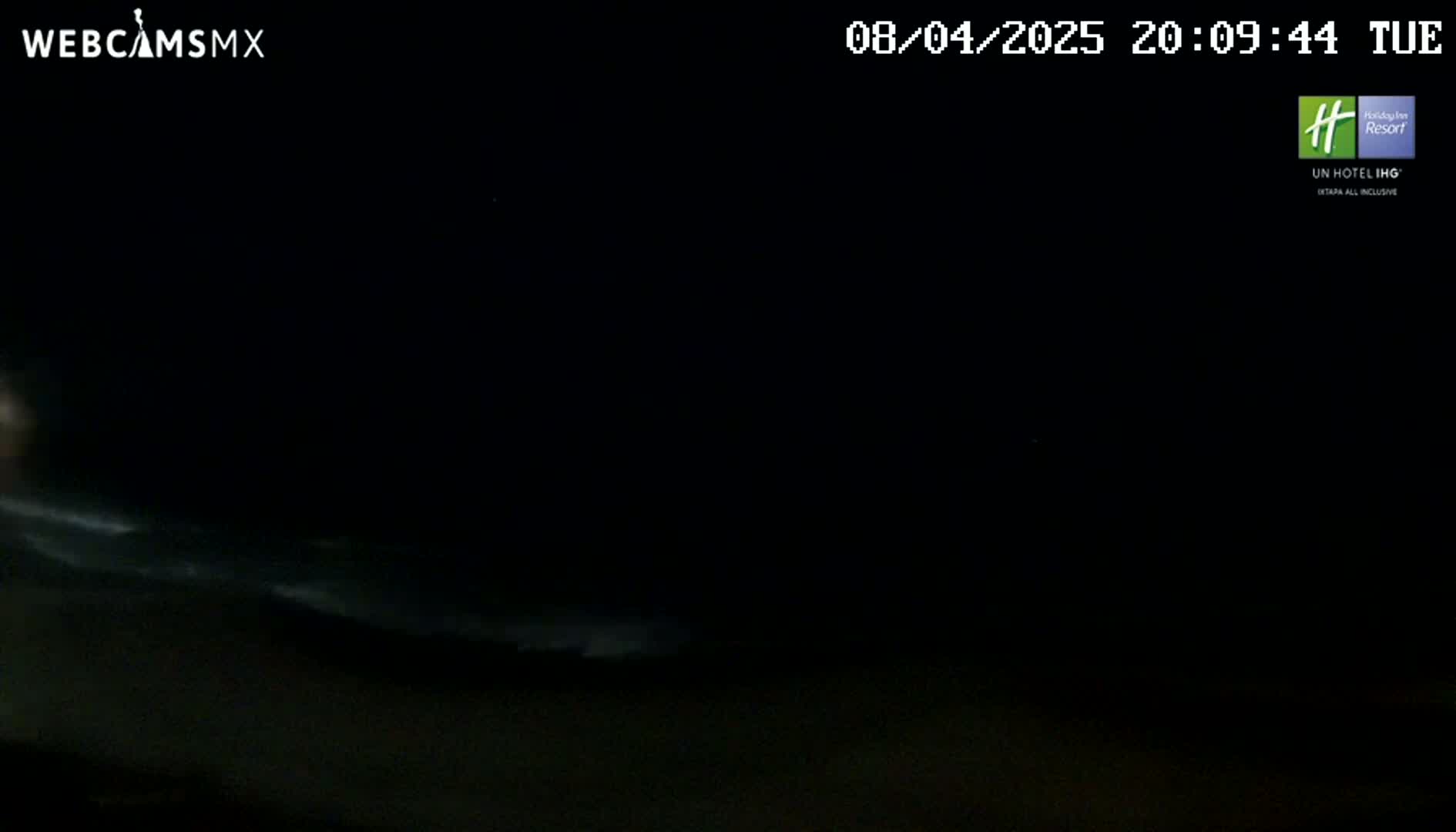 A dark, nighttime scene shows a faint, light-colored horizon line possibly indicating the ocean under a mostly clear sky.