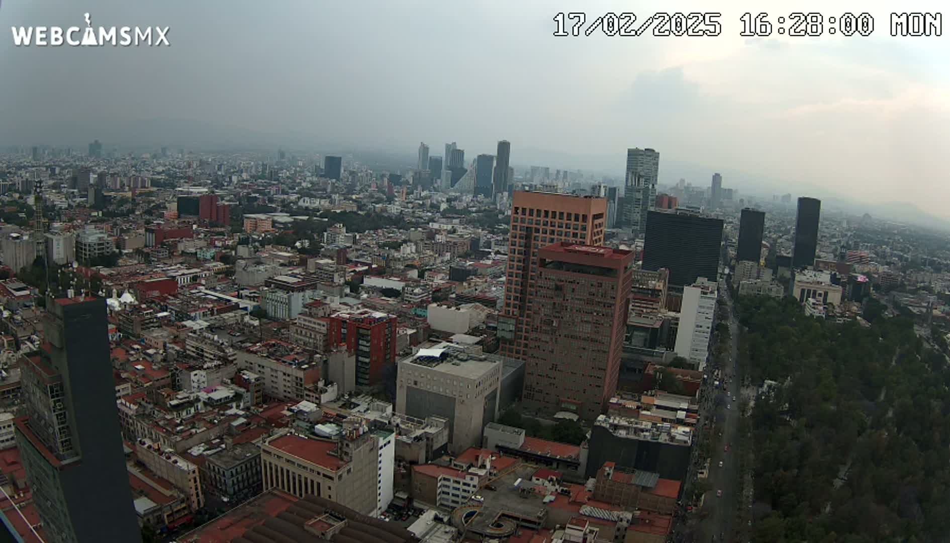 A hazy, overcast aerial view of a sprawling city with numerous high-rise buildings and dense urban development.