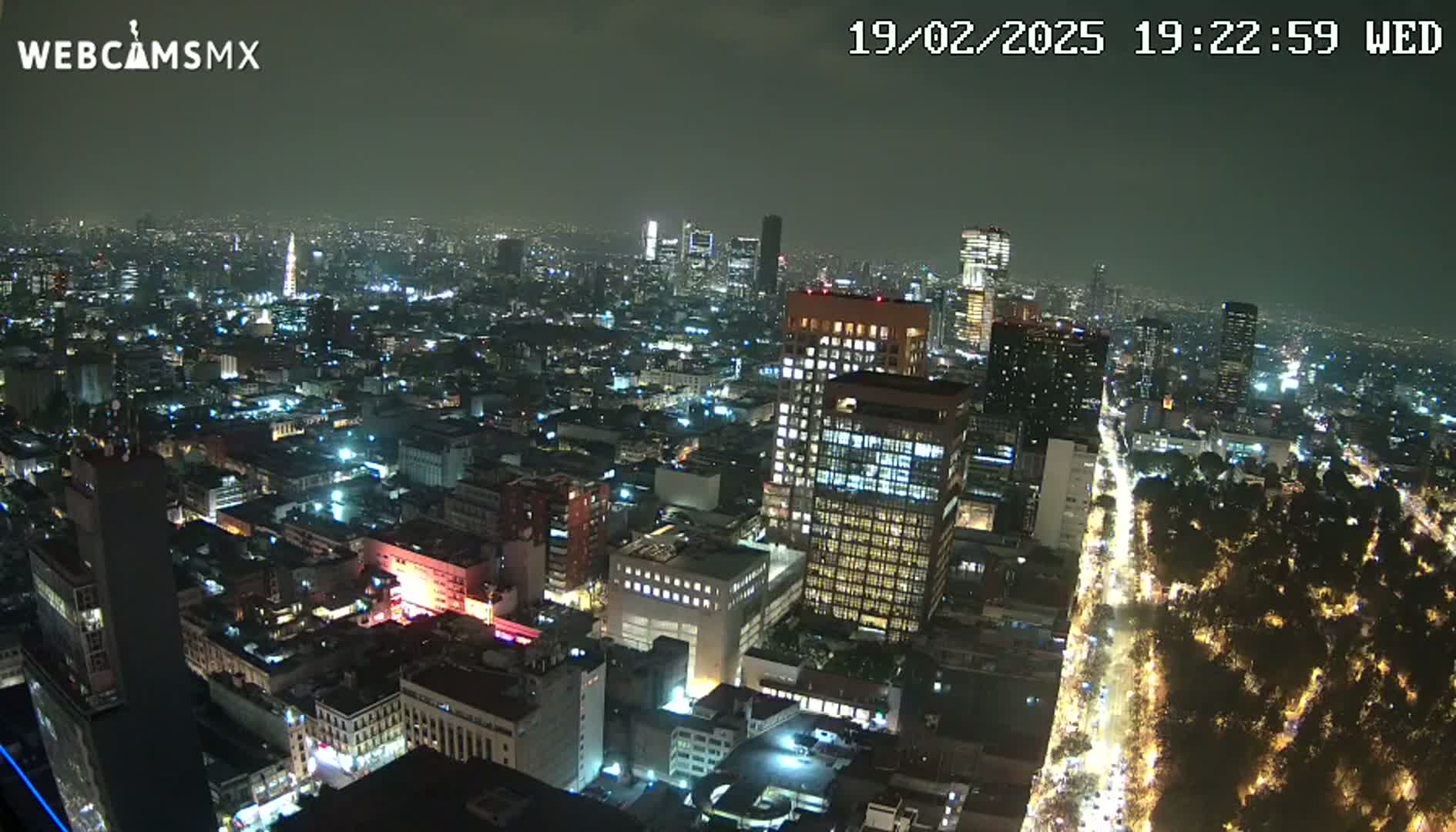 A nighttime aerial view of a large city with brightly lit buildings and streets, under a dark, clear sky.