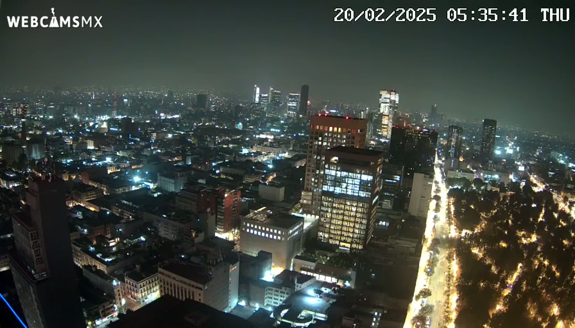 A nighttime aerial view of a brightly lit city, showing a network of streets and buildings.