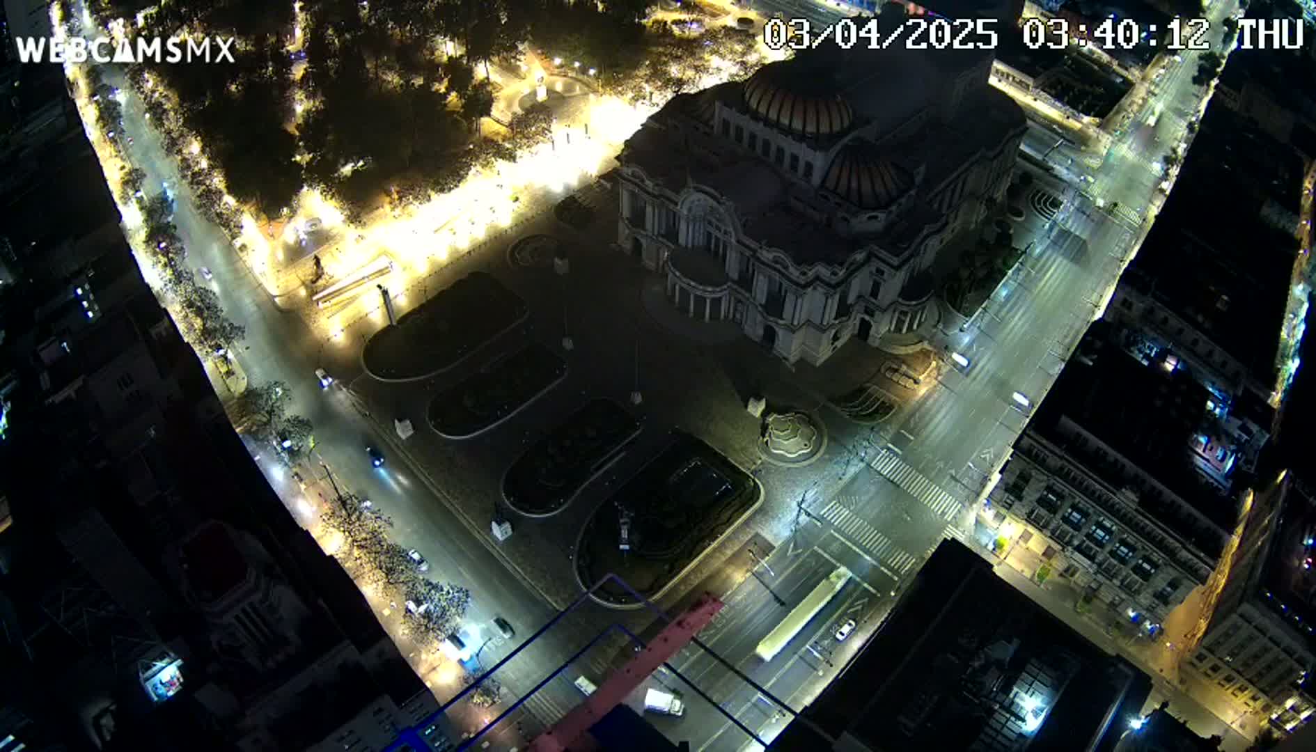 An aerial nighttime view shows a large building, possibly a museum, surrounded by city streets with sparse traffic and dimly lit surrounding areas.