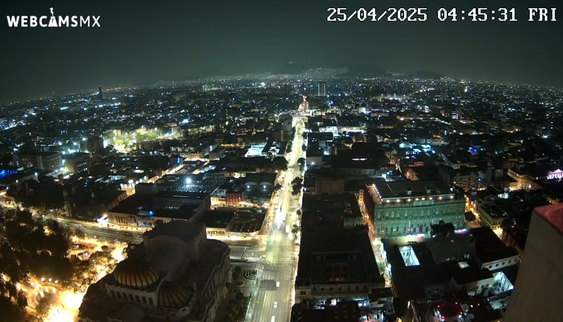 A nighttime aerial view of a city with brightly lit streets and buildings under a clear sky.